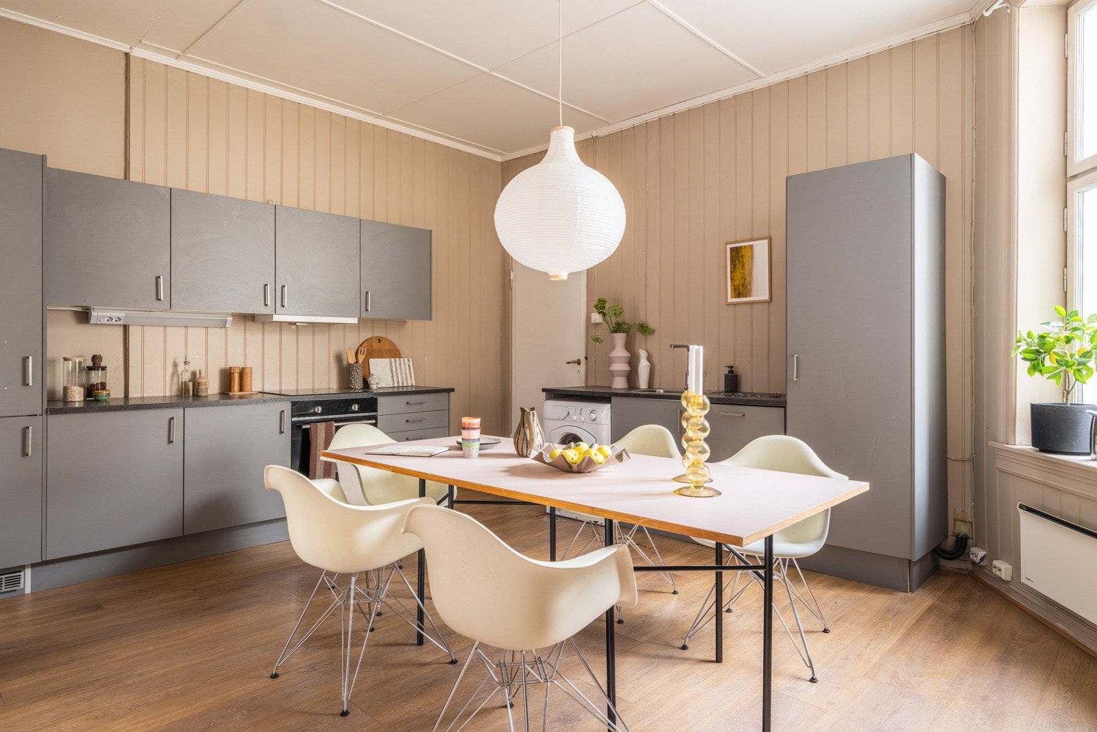 Et lyst og romslig spisekjøkken med enstavs laminat på gulv og panel på veggene malt i en fin farge. Galleribilde