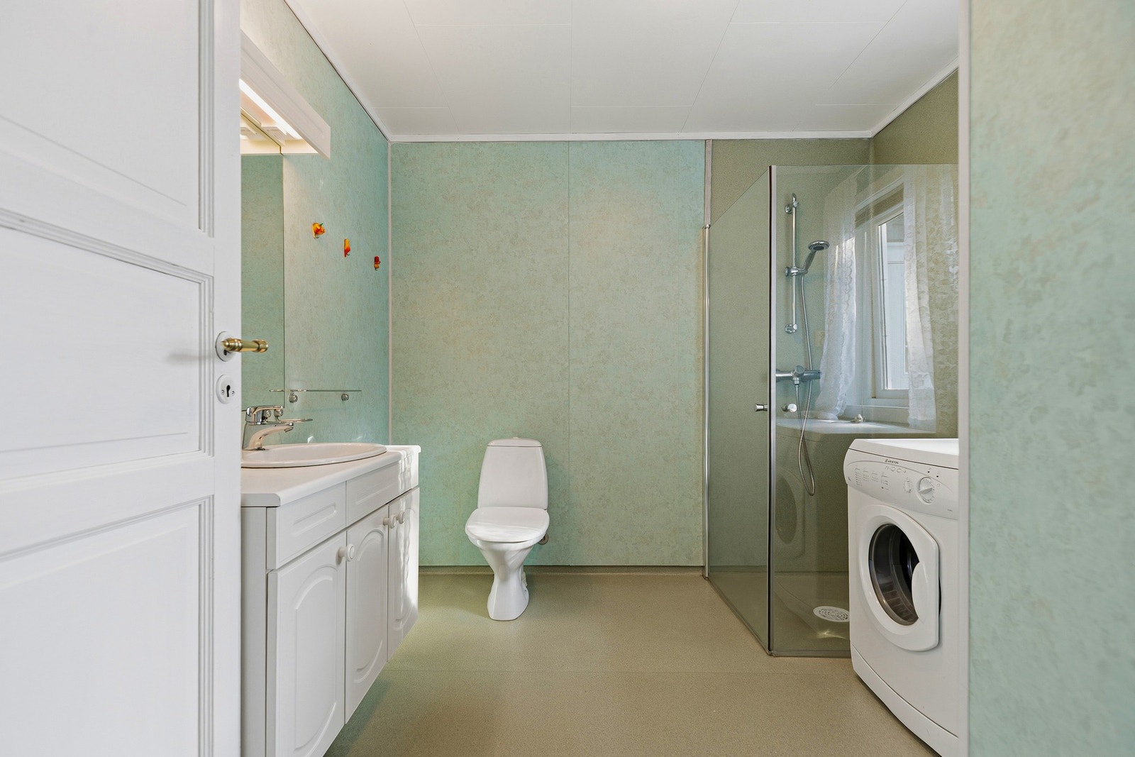 Baderom/vaskerom med servant, toalett og dusjkabinett. Opplegg for vaskemaskin og tørketrommel. Galleribilde