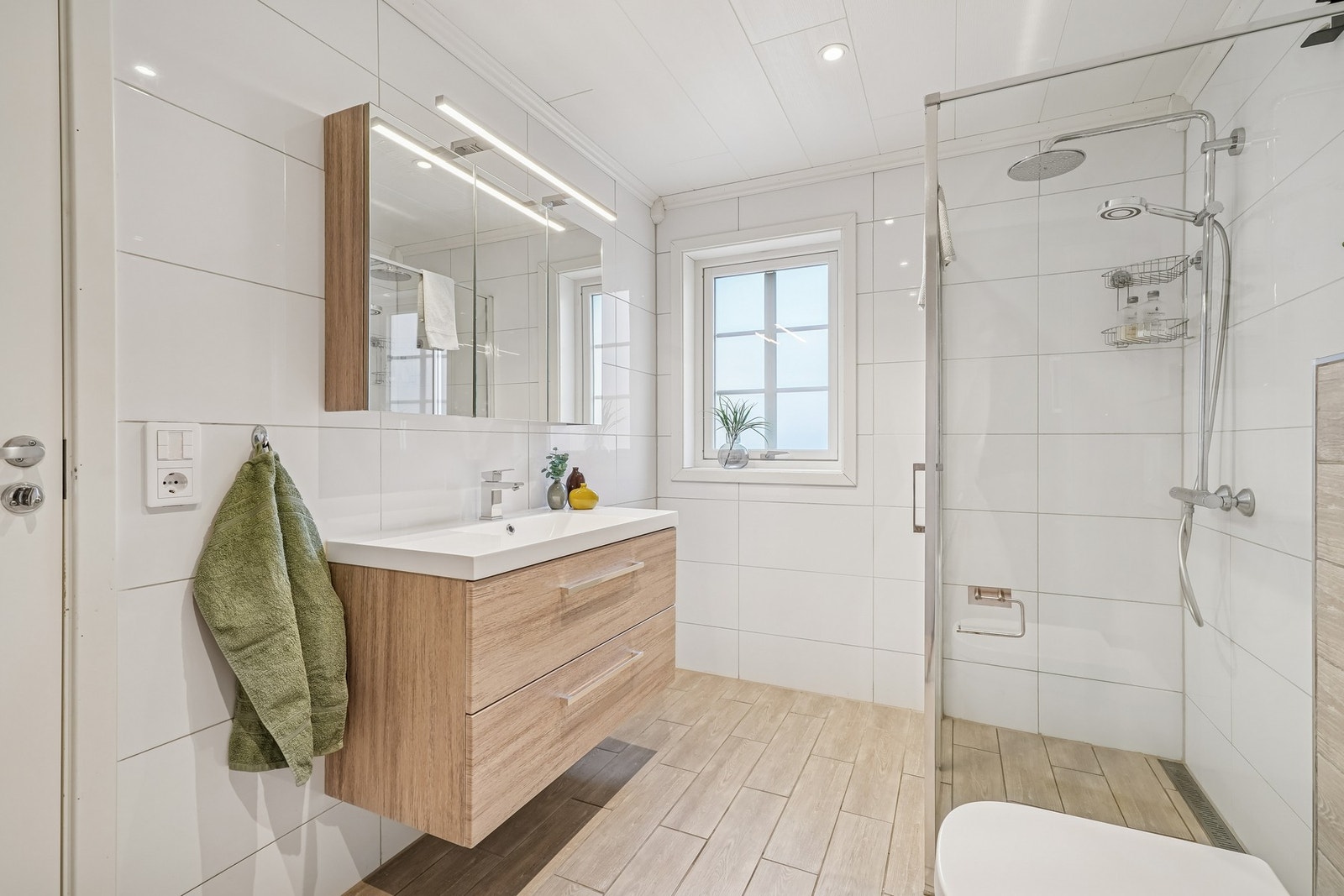 Pen innredning med skuffefronter og helstøpt servant over. Romslig speilskap med belysning over. Galleribilde