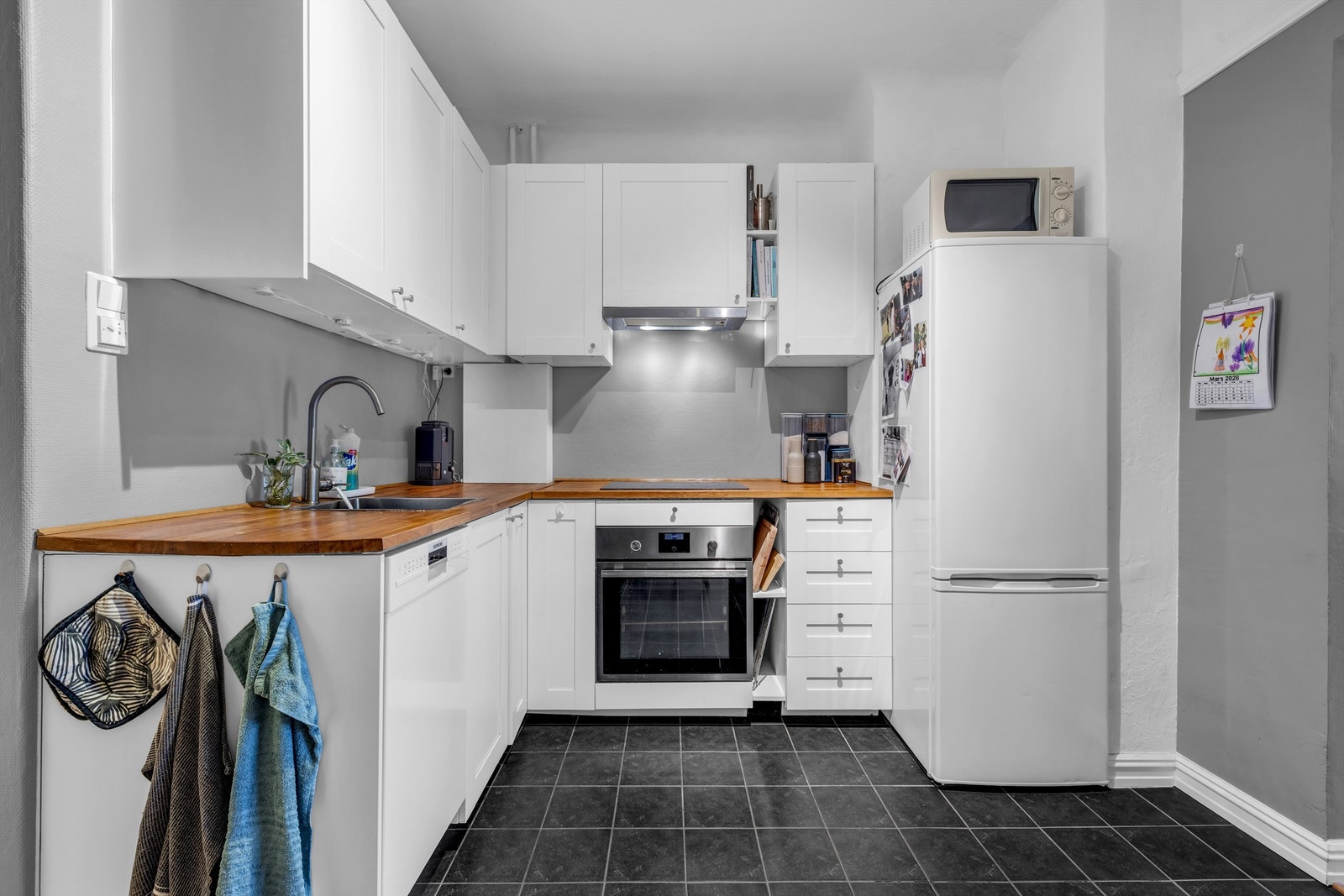 Kjøkkenet er innredet med profilerte skapfronter og benkeplate i treverk/laminat med trestruktur og nedfelt oppvaskkum i benkeplaten. Galleribilde