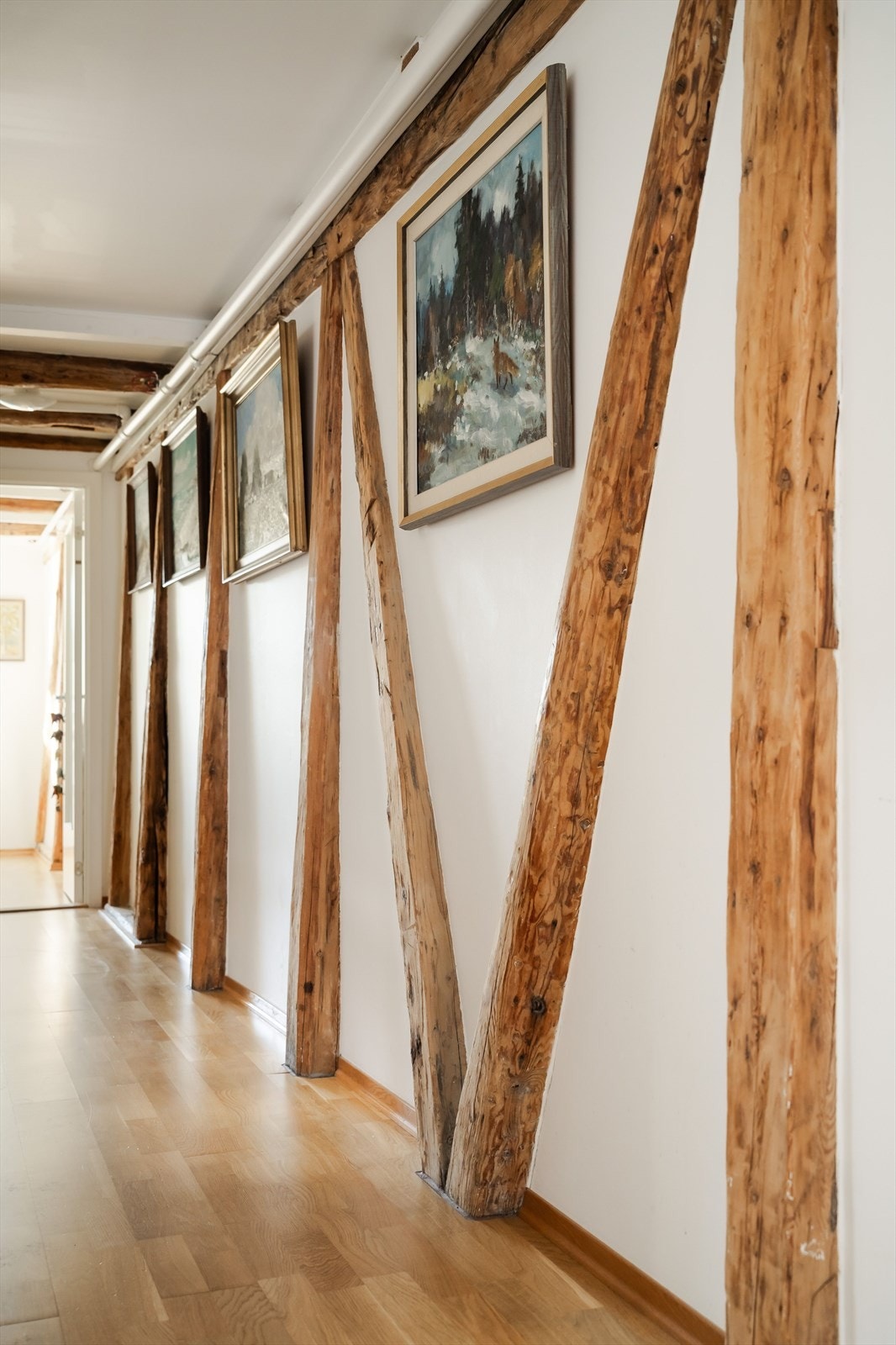 Langs én hel vegg i entreen er det synlige, originale trebjelker i fin kontrast. Galleribilde