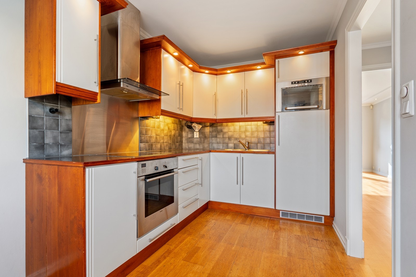 Kjøkken har dobbel vask nedfelt i laminatbenkeplate med spotter over benkeplata, keramisk koketopp, int. stekeovn, int. kjøleskap og int. micro. Galleribilde