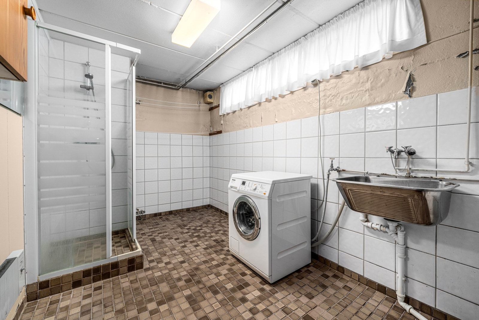 Bad/vaskerom med dusjkabinett og opplegg for vaskemaskin samt utslagsvask. Galleribilde