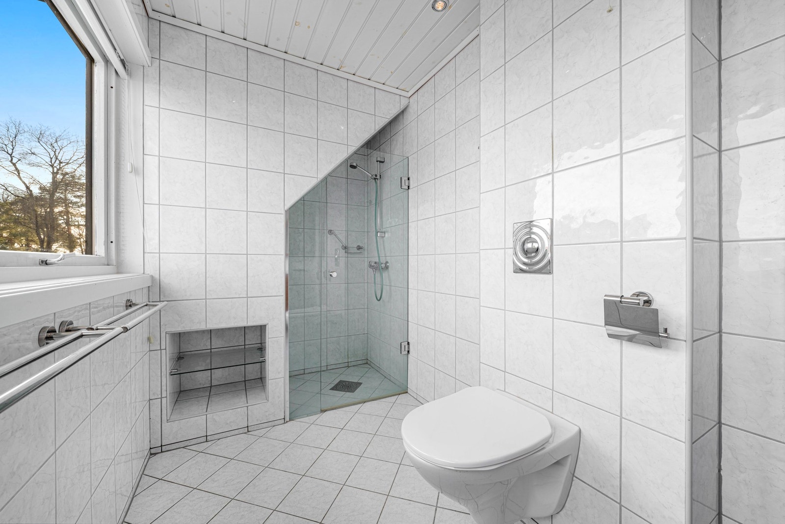 Badet har dusjløsning med glassvegg og flislagte overflater for et tidløst uttrykk. Galleribilde