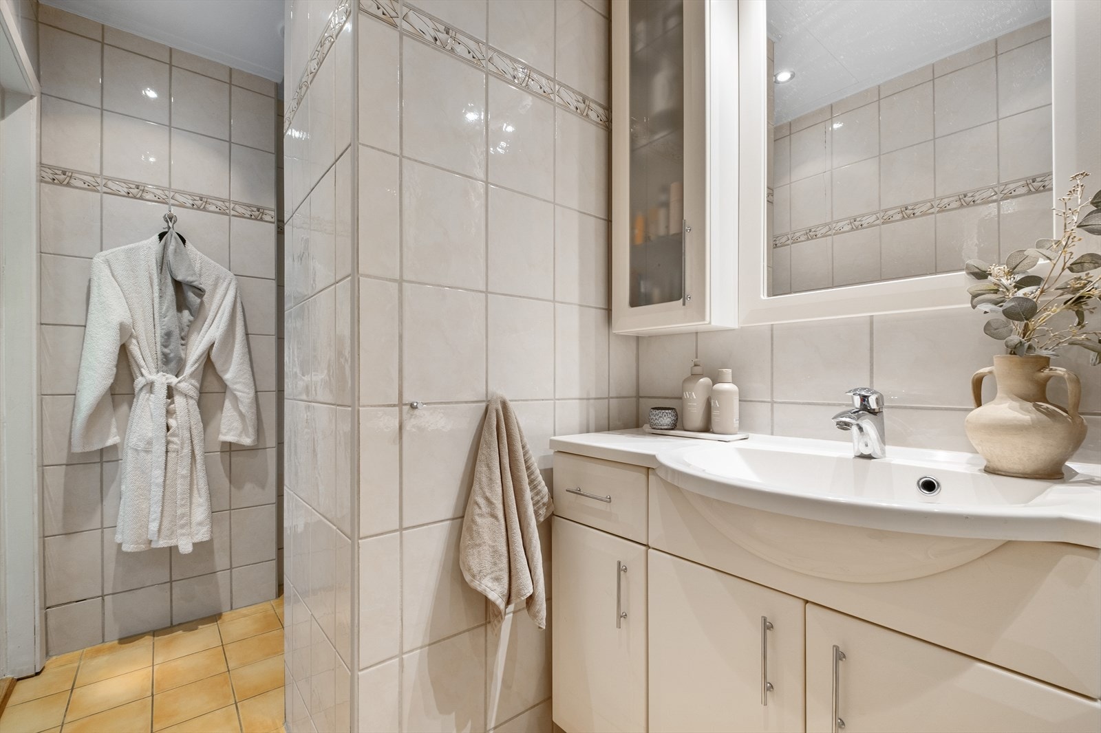 Badet er praktisk innredet og har flislagte gulv og vegger som gir et helhetlig og slitesterkt uttrykk. Galleribilde