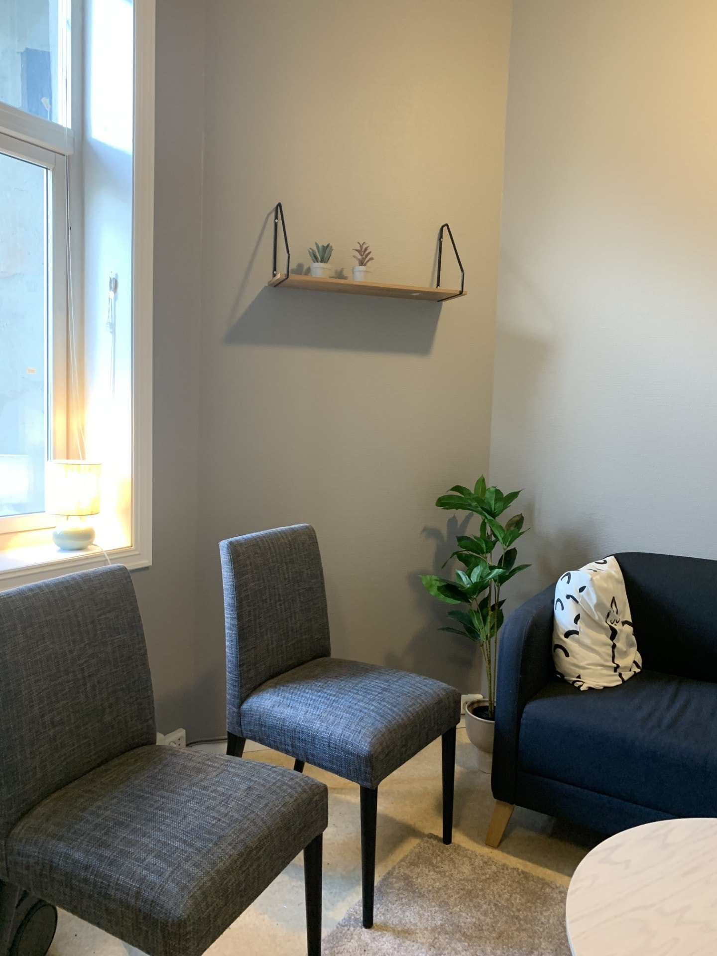 Stue for bofellesskapet E, møblert med sofa, stoler, teppe, hylle, sofabord, og lampe Galleribilde