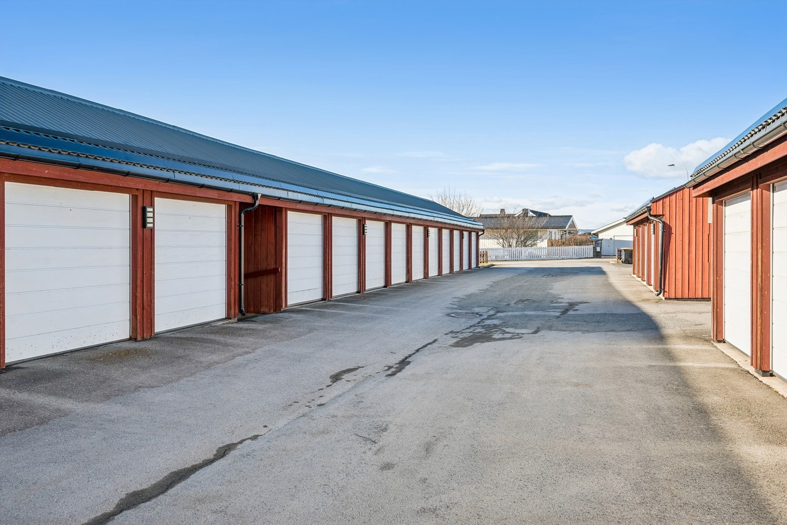 Garasjeplassen er utstyrt med fjernstyrt port, strøm og opplegg for elbillader. I tillegg medfølger to boder i kjelleren. Galleribilde