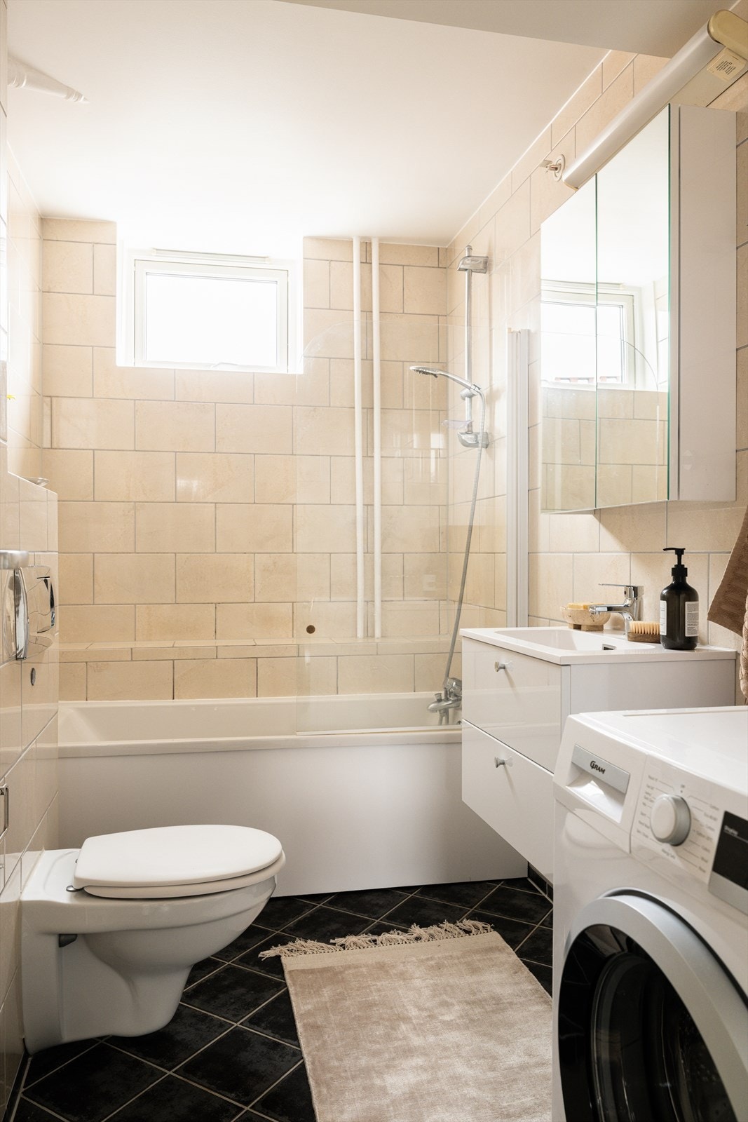 Badet er innredet med servant på servantskap, speilskap, toalett og badekar med dusj. Galleribilde