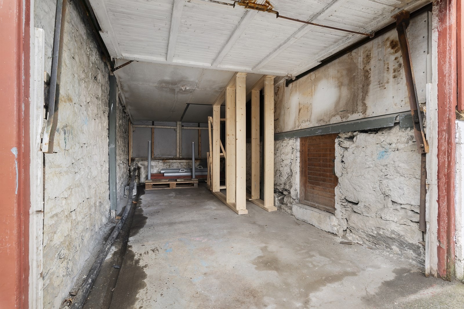 Her ser vi innsiden av garasjen. Det er satt opp midlertidig forsterkning av taket, da det skal føres opp et stillas på garasjetaket for maling av veggen. Galleribilde