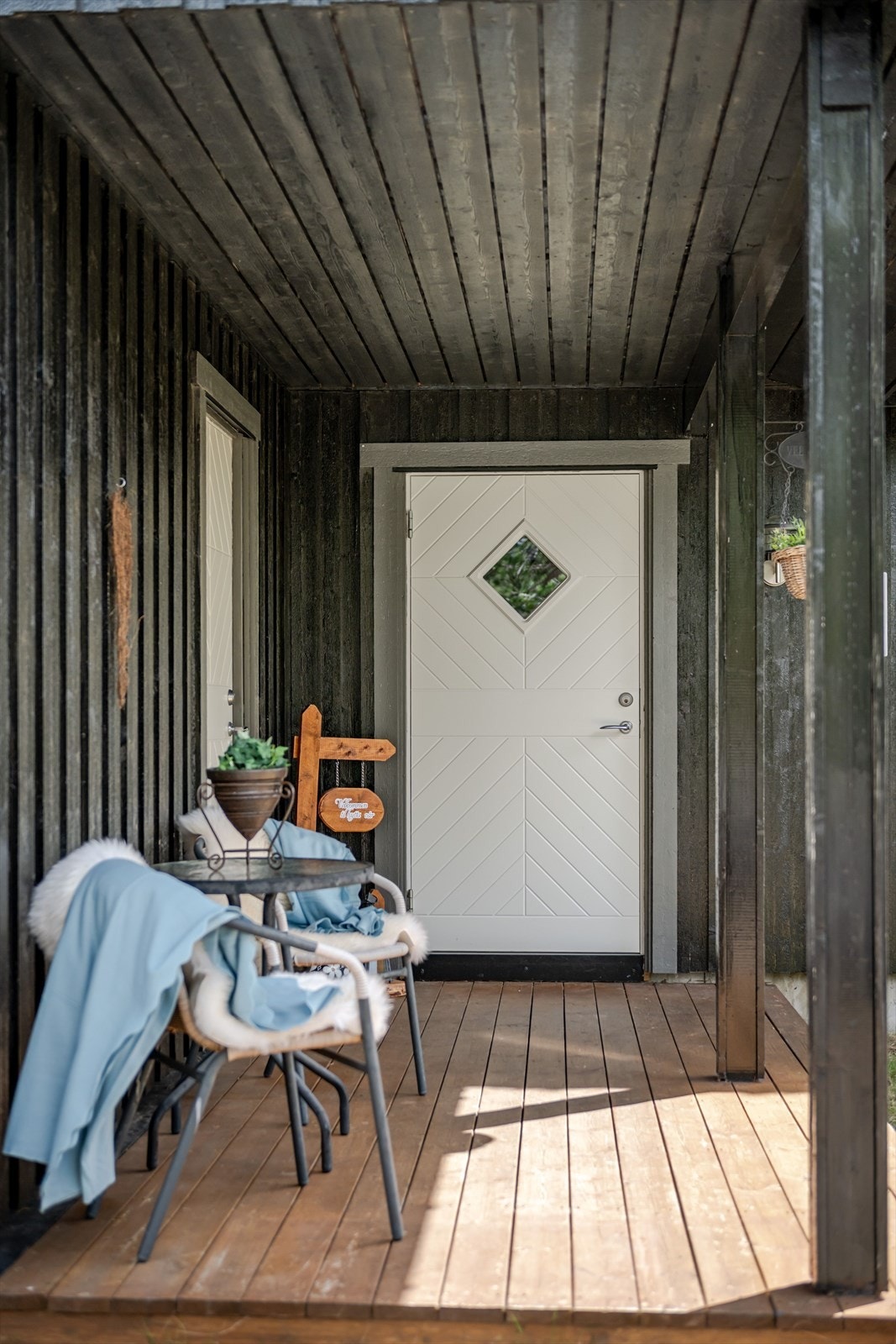 Overbygd inngangsparti med panelkledd vegg gir beskyttelse mot vær og vind. Galleribilde