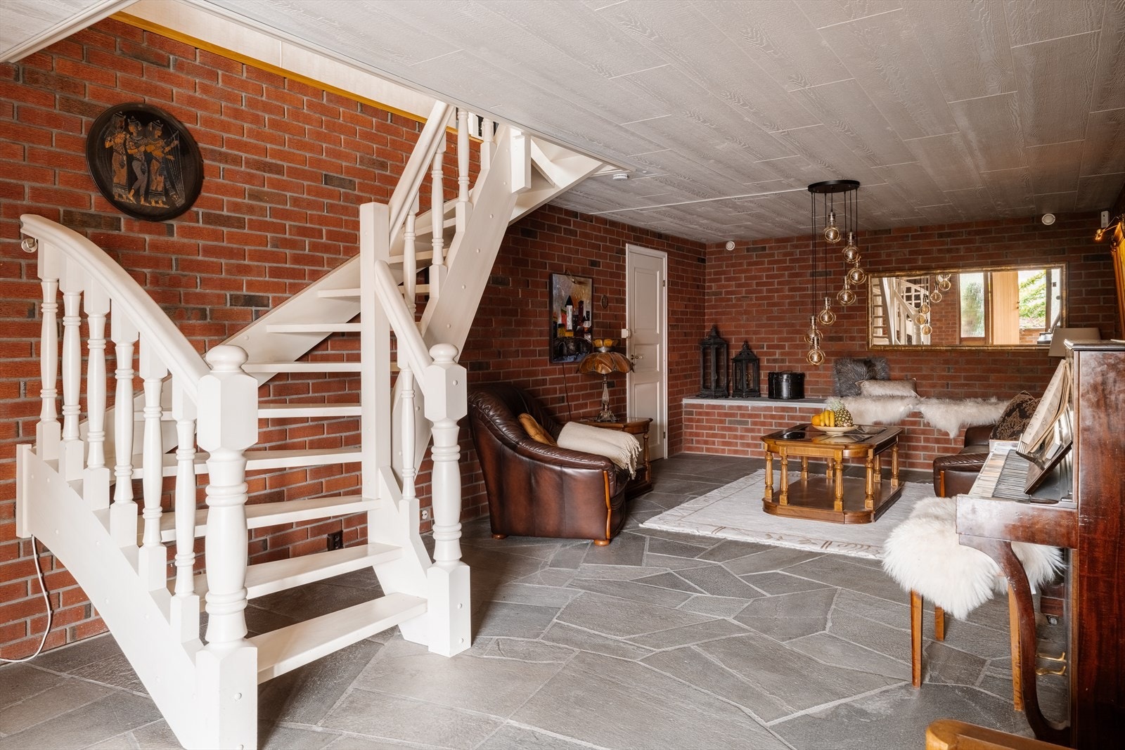 Inngangspartiet går over i en romslig kjellerstue med karakteristiske vegger i teglstein. Galleribilde