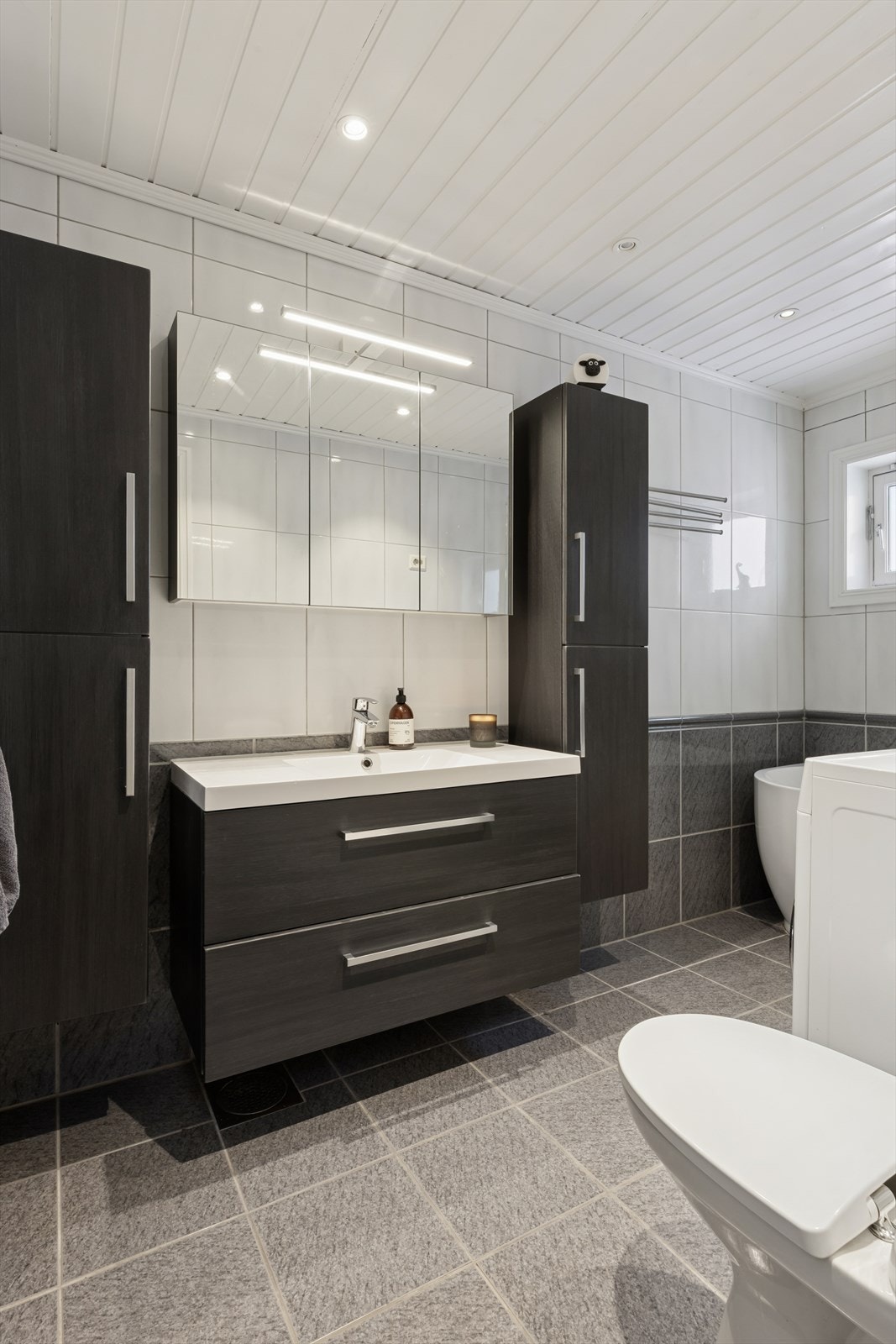 Badet i hoveddelen har badekar med dusjvegg, varmekabler i gulvet og god skapplass. Galleribilde