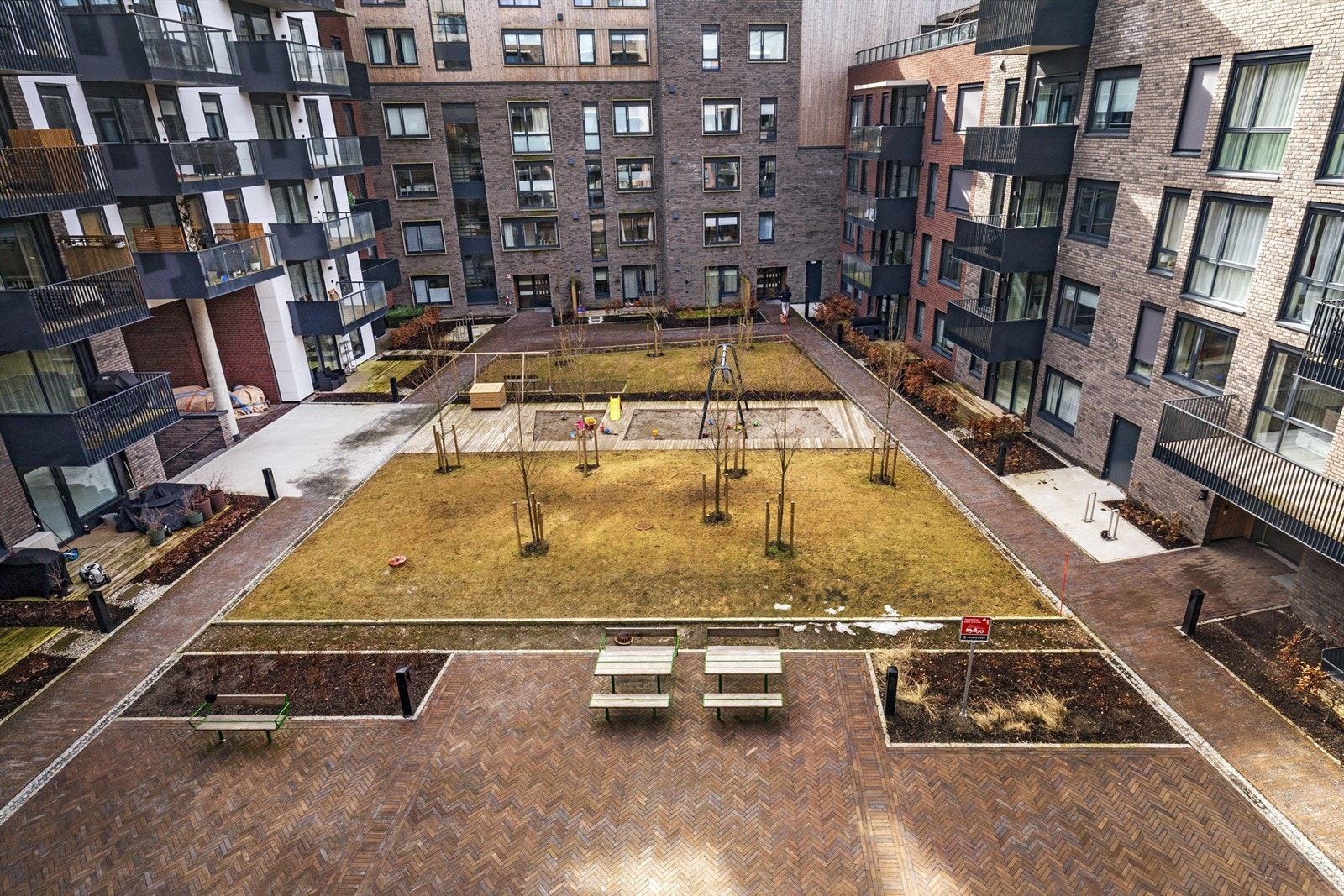 Hyggelig bakgård med sittegrupper, gressplen og lekeplass for de yngste beboerne i borettslaget Galleribilde