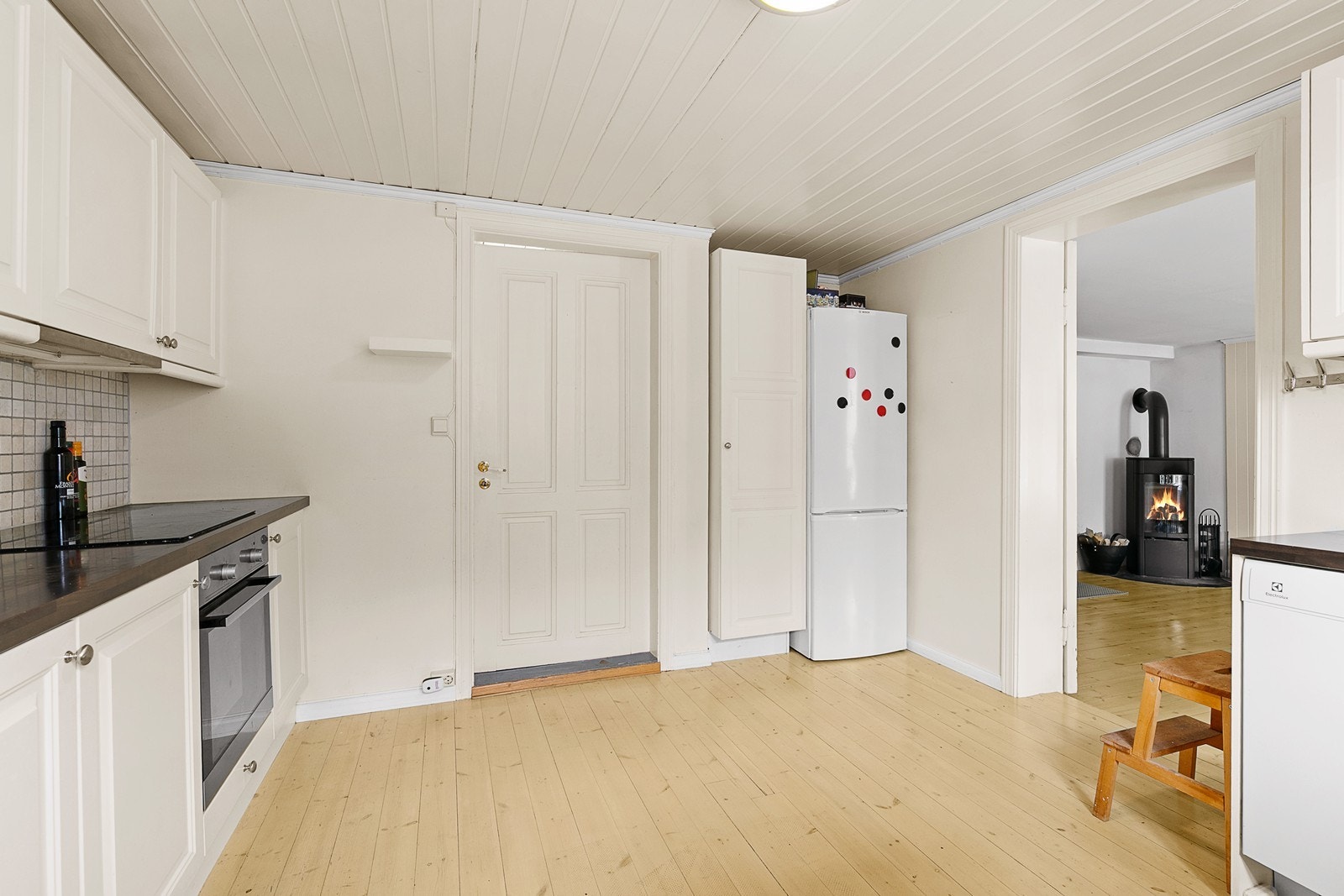 Romslig og lyst kjøkken med innredning med hvite profilerte fronter og laminat benkeplate. Galleribilde