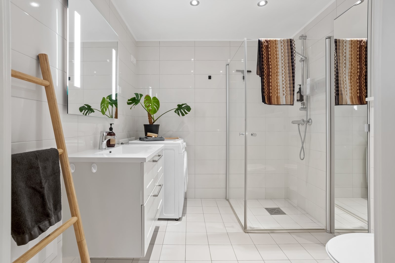 Badet er utstyrt med moderne baderomsinnredning som dusjhjørne med innfellbare glassdører, vegghengt toalett, servant med underskap, speil på vegg med lys, downlights i himling, samt varmekabler i gulvet. Galleribilde