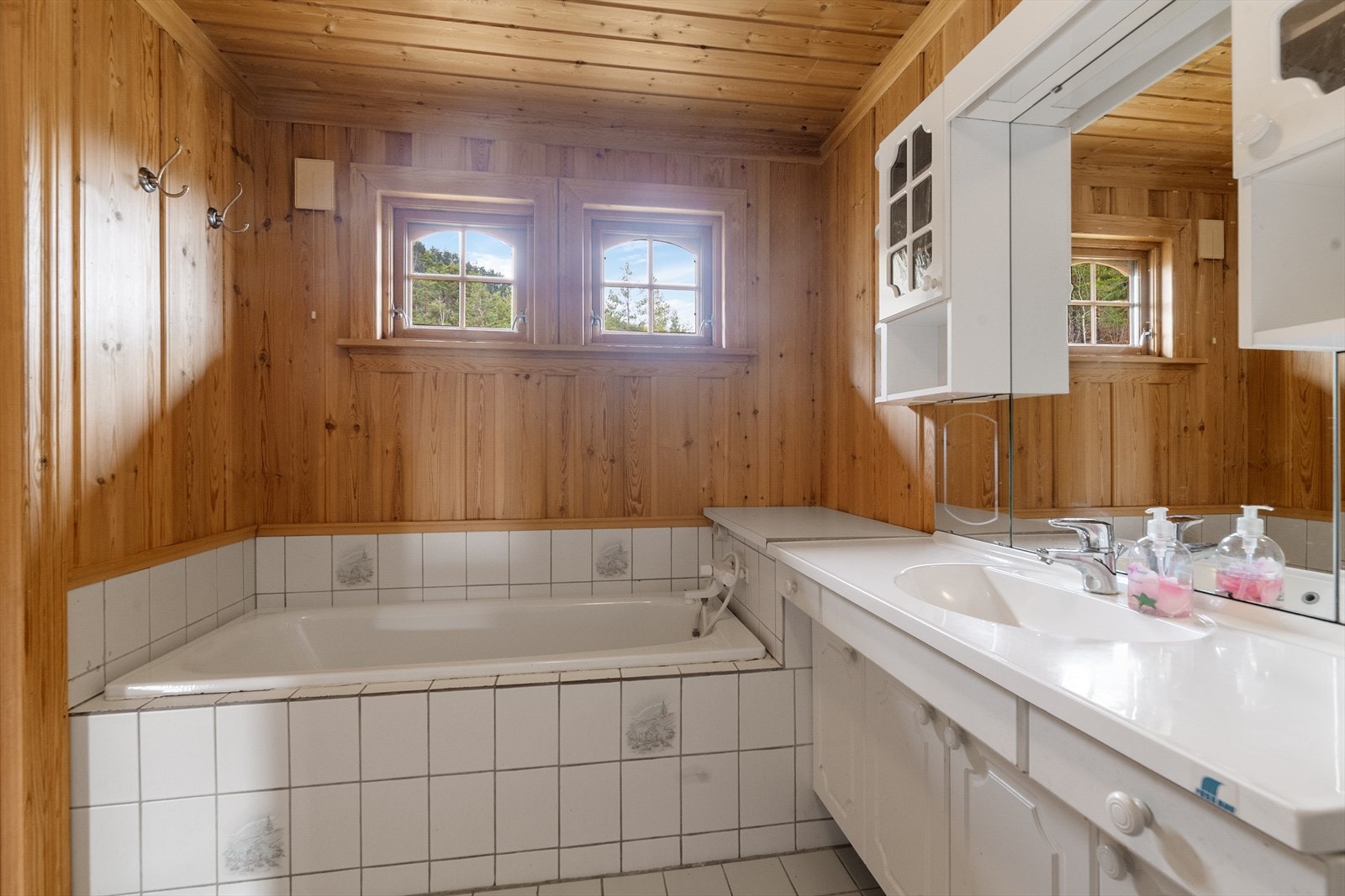 Badet inneholder heldekkende servant med underskap, overskap med lys, speil, dusjkabinett, gulvmontert toalett og badekar. Galleribilde