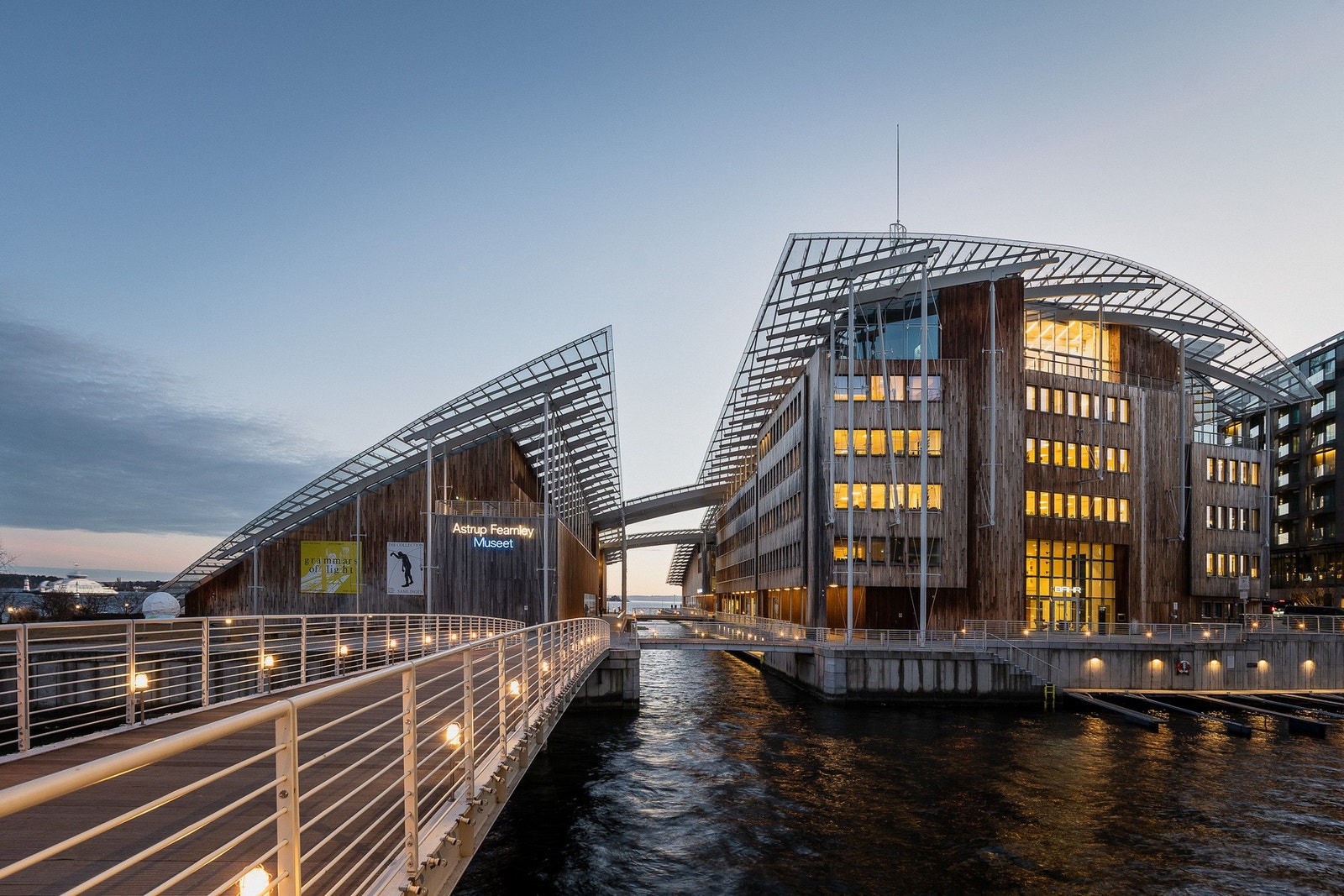Astrup Fearnley Museet fremstår som et arkitektonisk landemerke, vakkert opplyst mot kveldshimmelen. Galleribilde