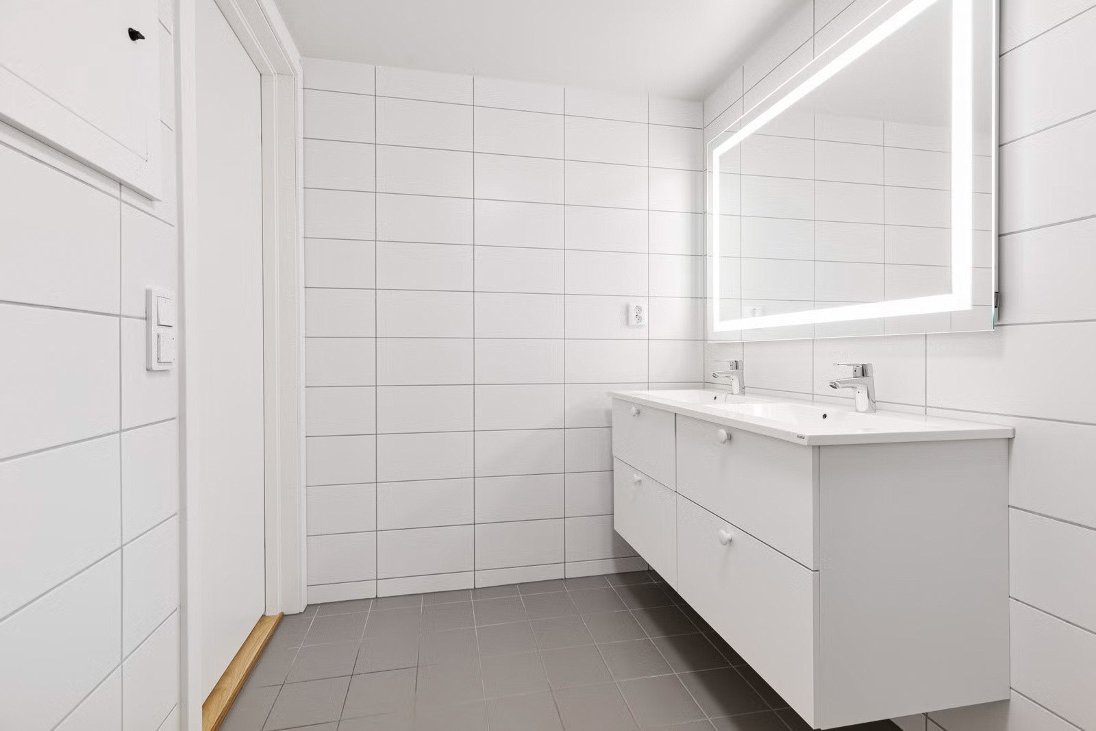 Badet er innredet med dusjhjørne, veggmontert toalett og dobbel servant Galleribilde