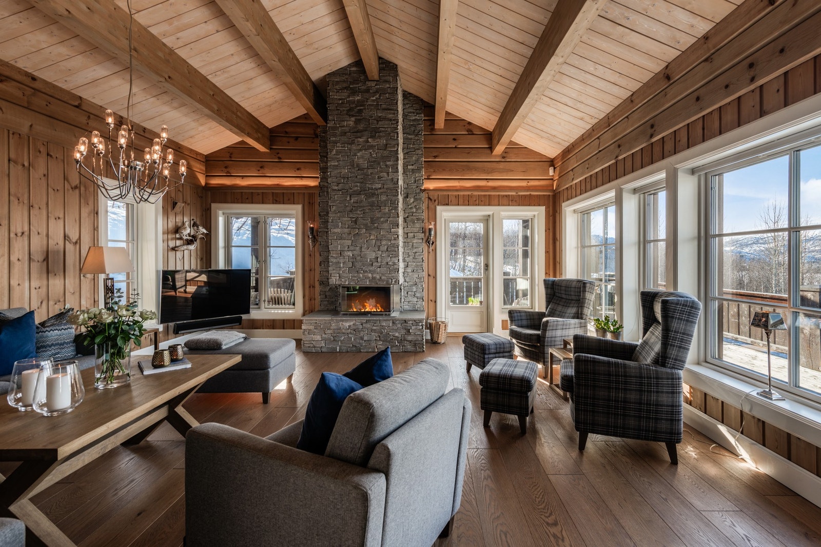 Eksklusiv stue med generøs takhøyde, gjennomgående kvalitetsmaterialer og store panoramavinduer som slipper naturen inn Galleribilde