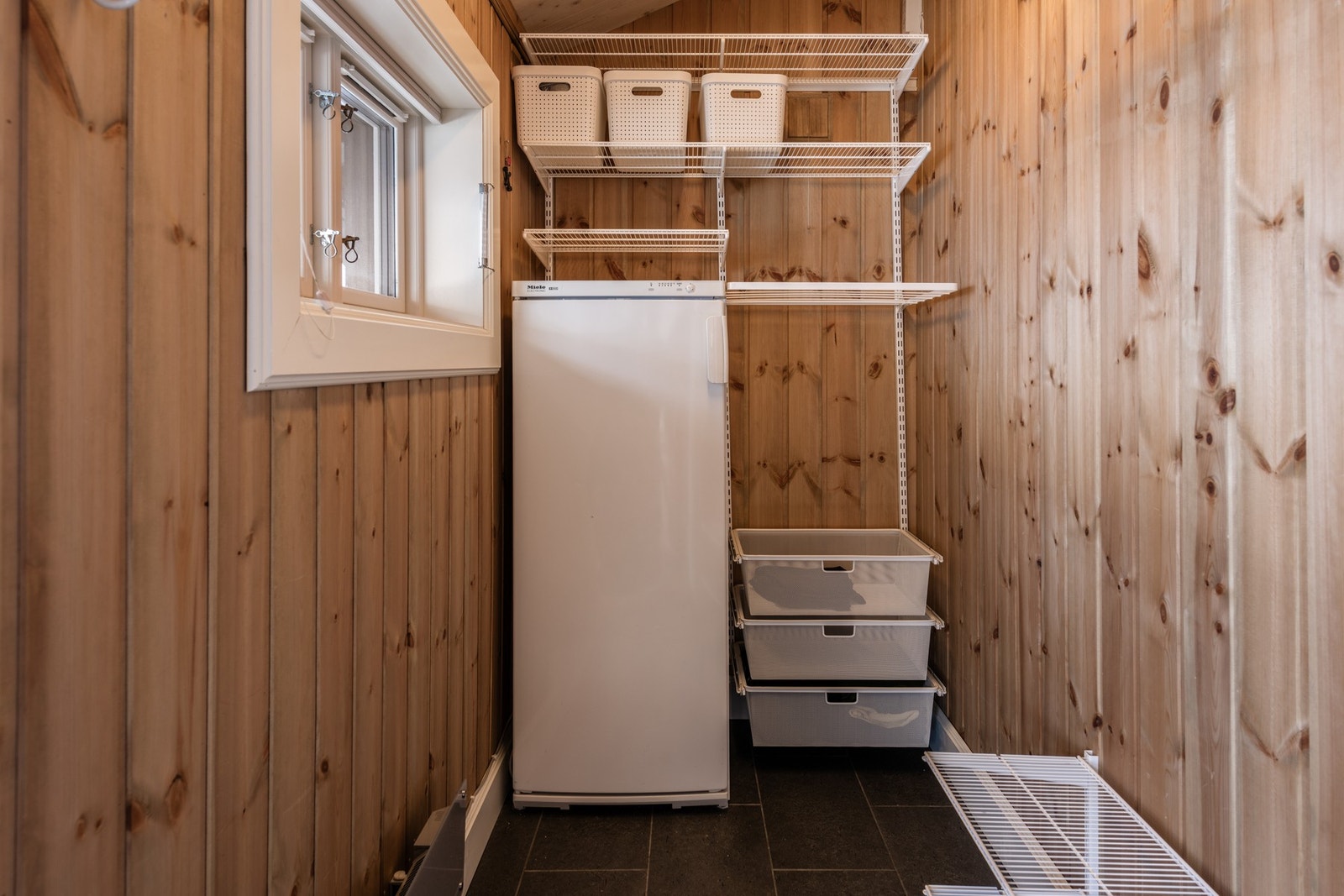 Praktisk bod med flislagt gulv og god oppbevaringsplass, med inngang utenfra Galleribilde