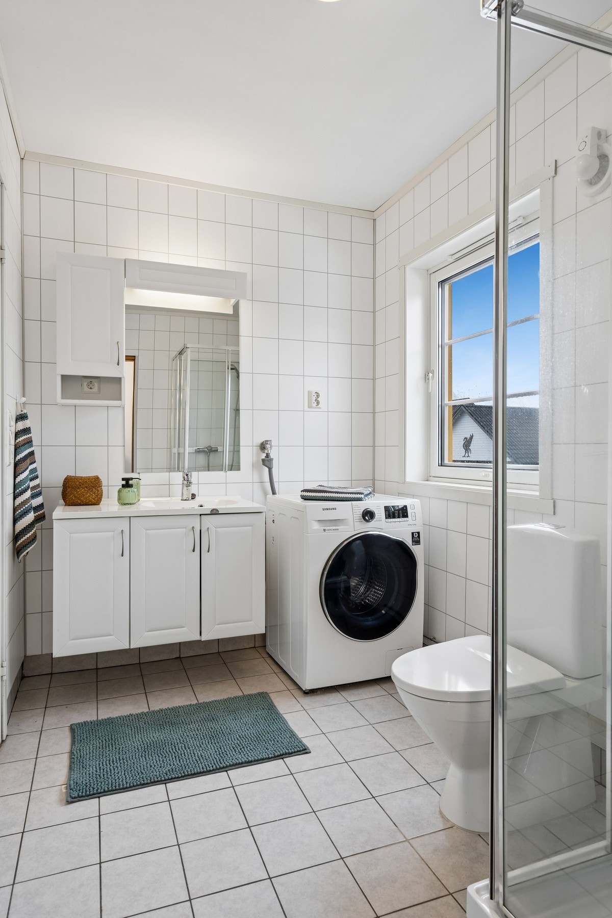 Badet har vegghengt innredning med stående toalett og dusjkabinett Galleribilde