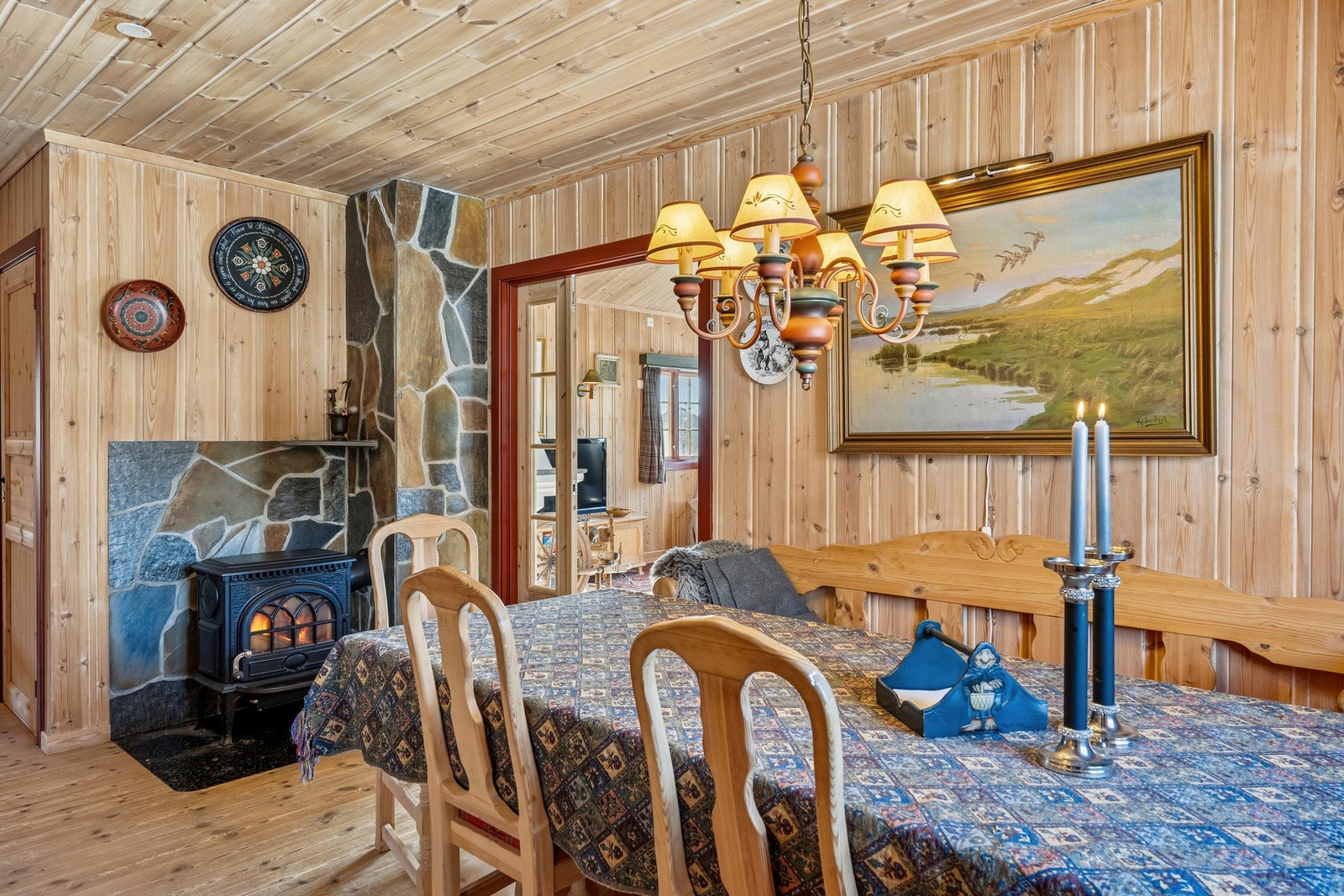 Kjøkken og spiseplass er en hyggelig sone for lange og rolige måltider, her er det plass til mange rundt bordet. Flott brannmur med skiferforblendet overflate samt Jøtul vedovn Galleribilde