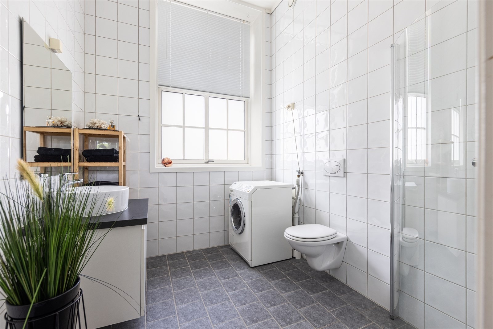 Romslig, helfliset bad med servantskap, overliggende vask og speil. Galleribilde