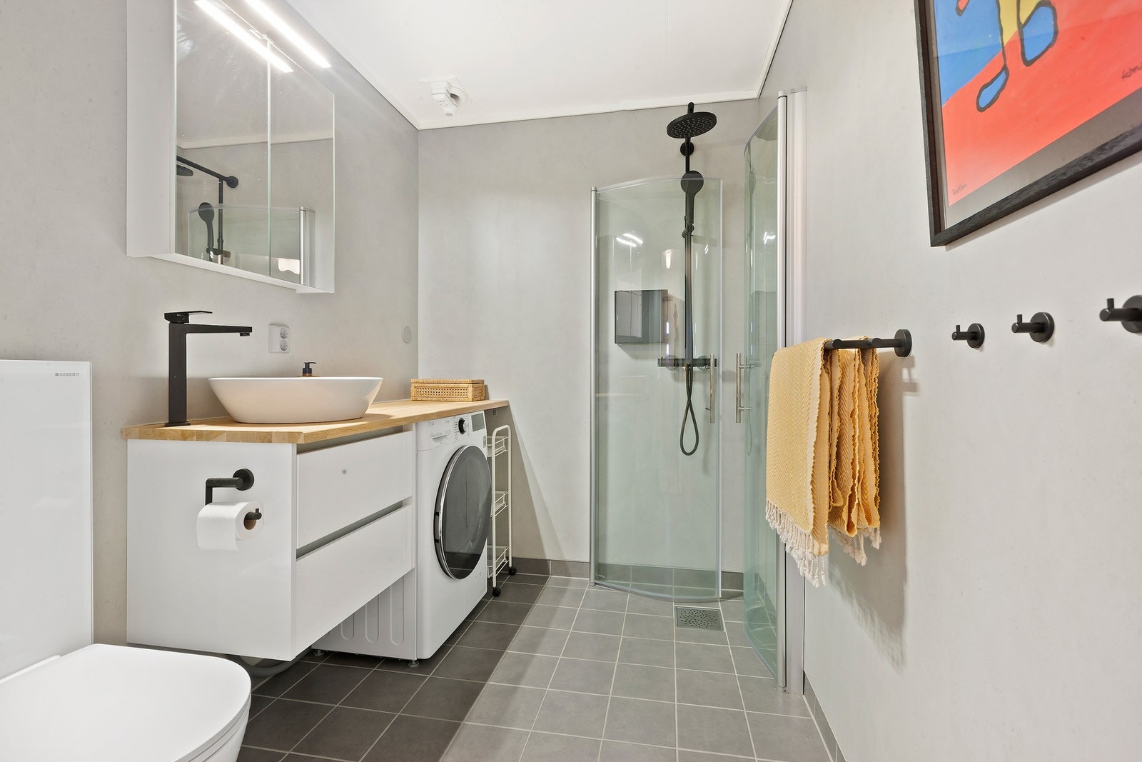 Bad med dusjhjørne, servant med underskap og opplegg for vaskemaskin. Galleribilde