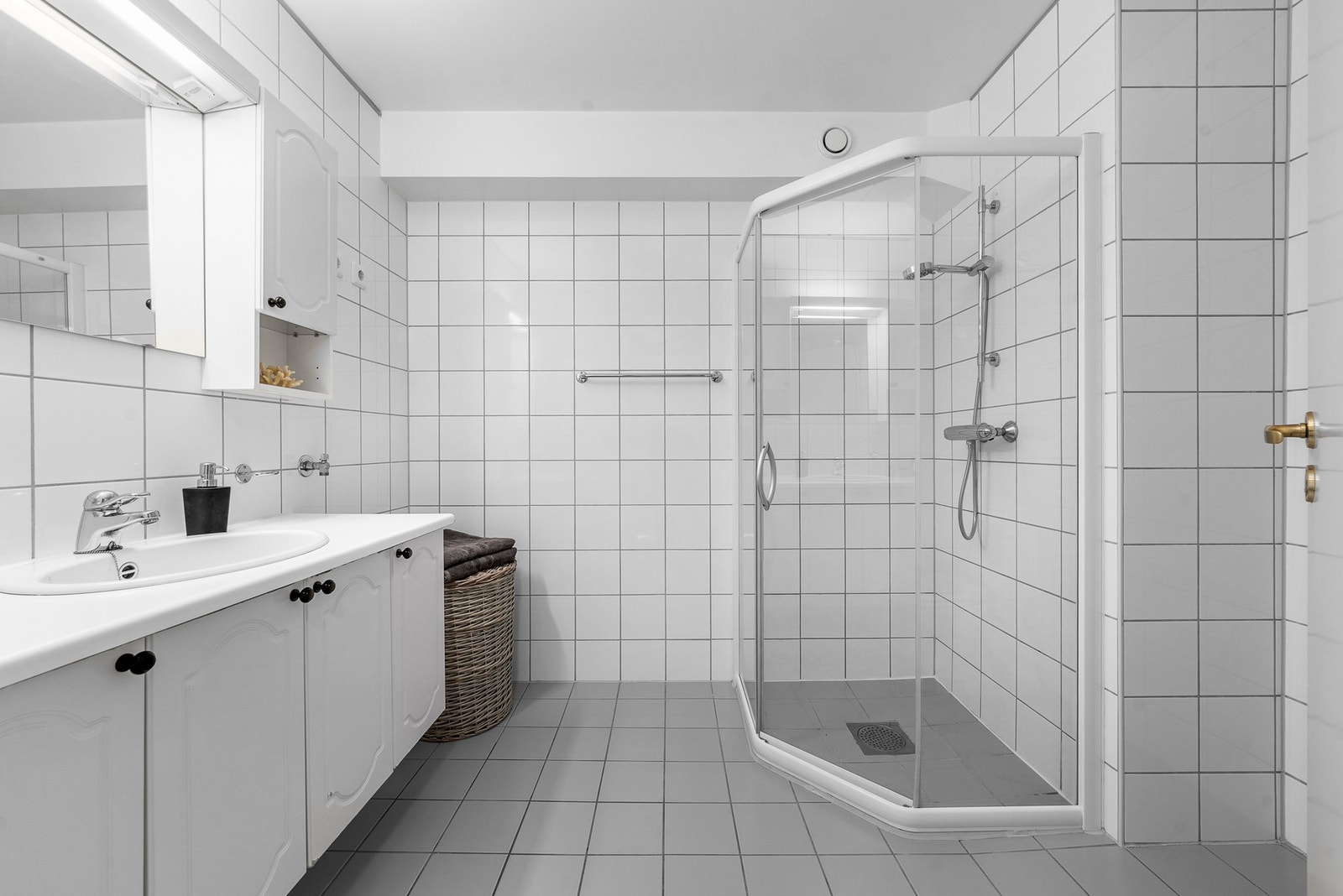 Romslig bad med flislagte overflater, dusjhjørne med glassvegger og dobbel servantinnredning. God oppbevaringsplass og et lyst, tidløst uttrykk. Galleribilde