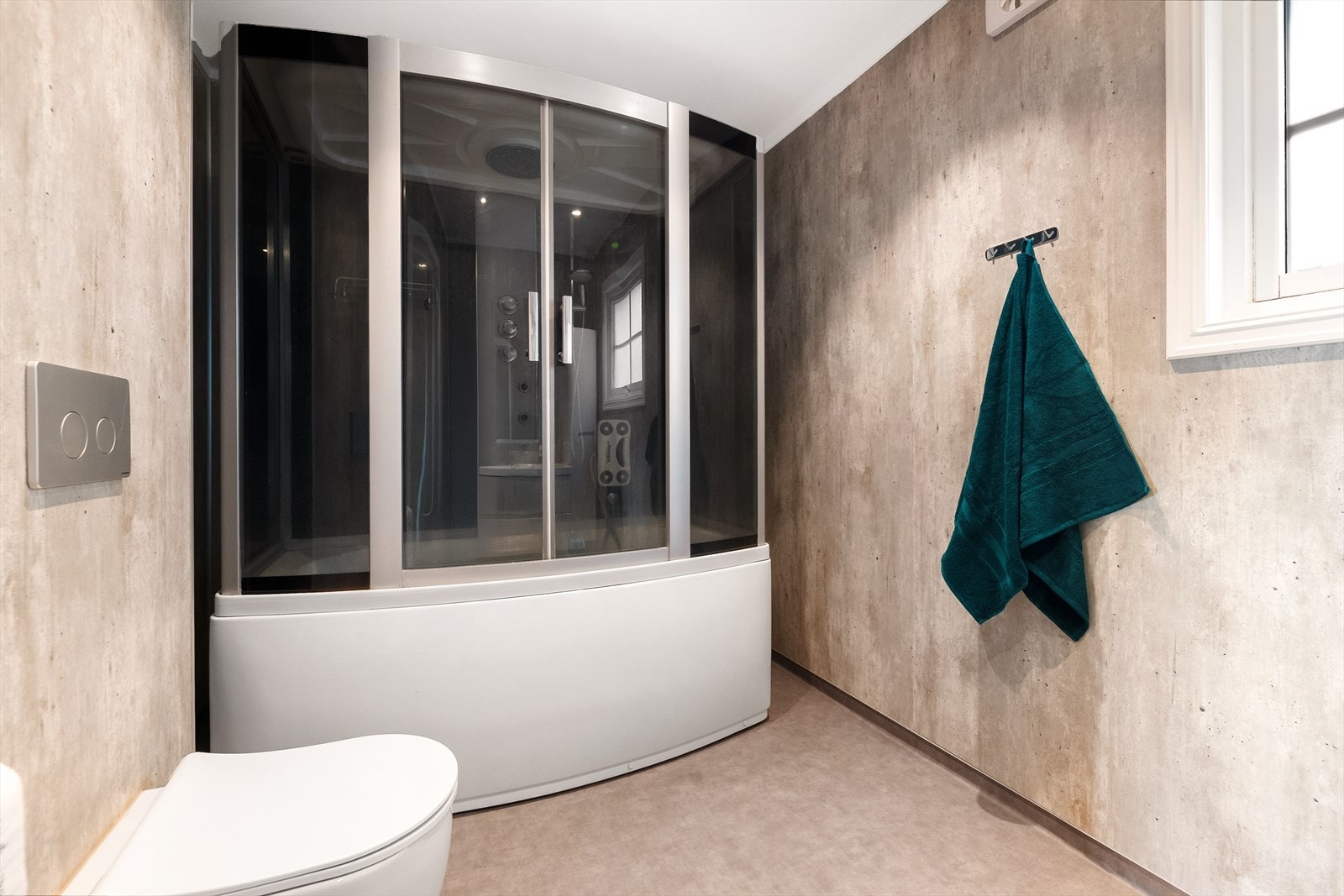 Flott bad innredet med veggmontert toalett, dusjkabinett og servantinnredning med skuffer, skap og speil. Galleribilde