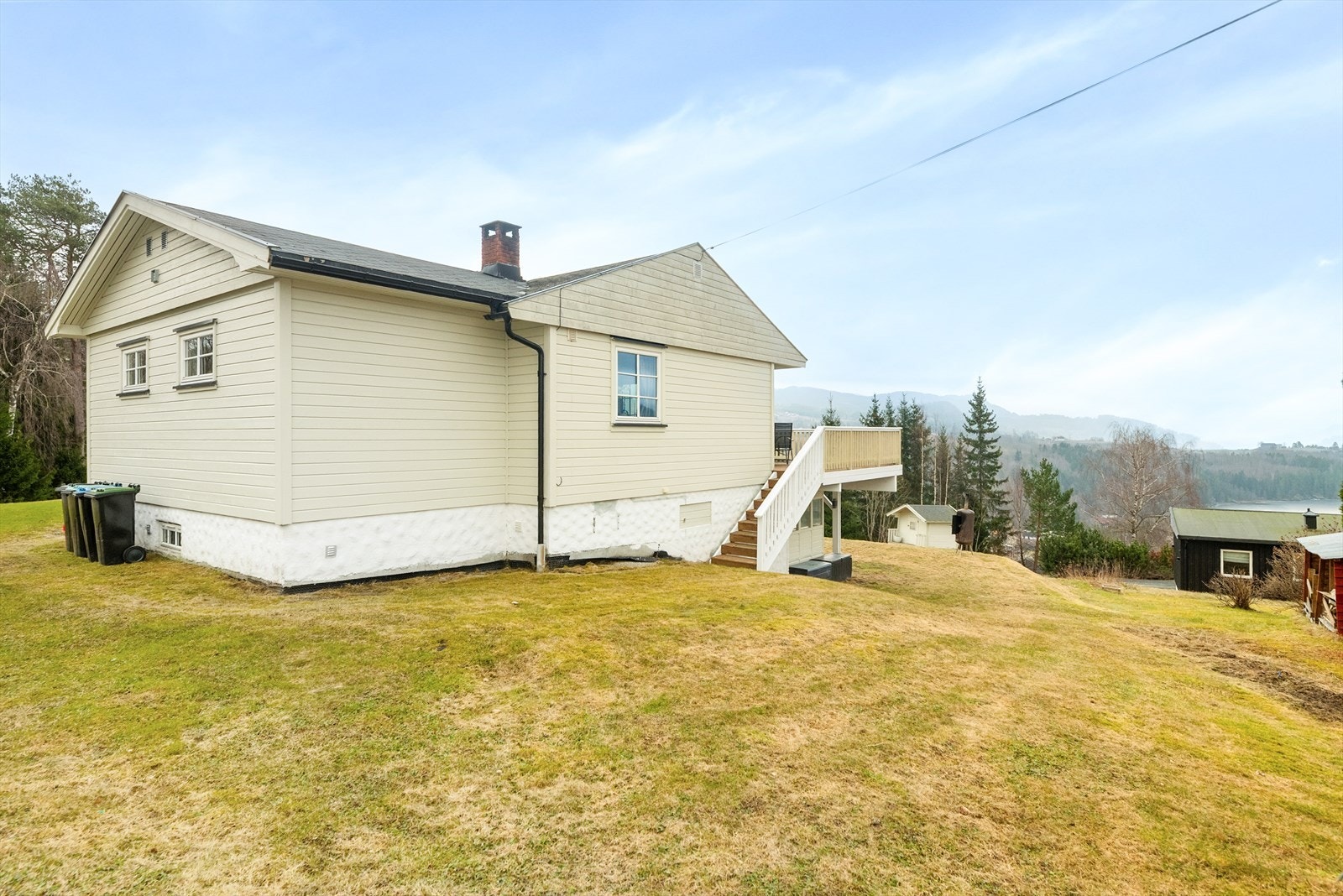 Fra verandaen er det nedgang til hagen. På eiendommen er det også garasje med bod og lekestue. Galleribilde