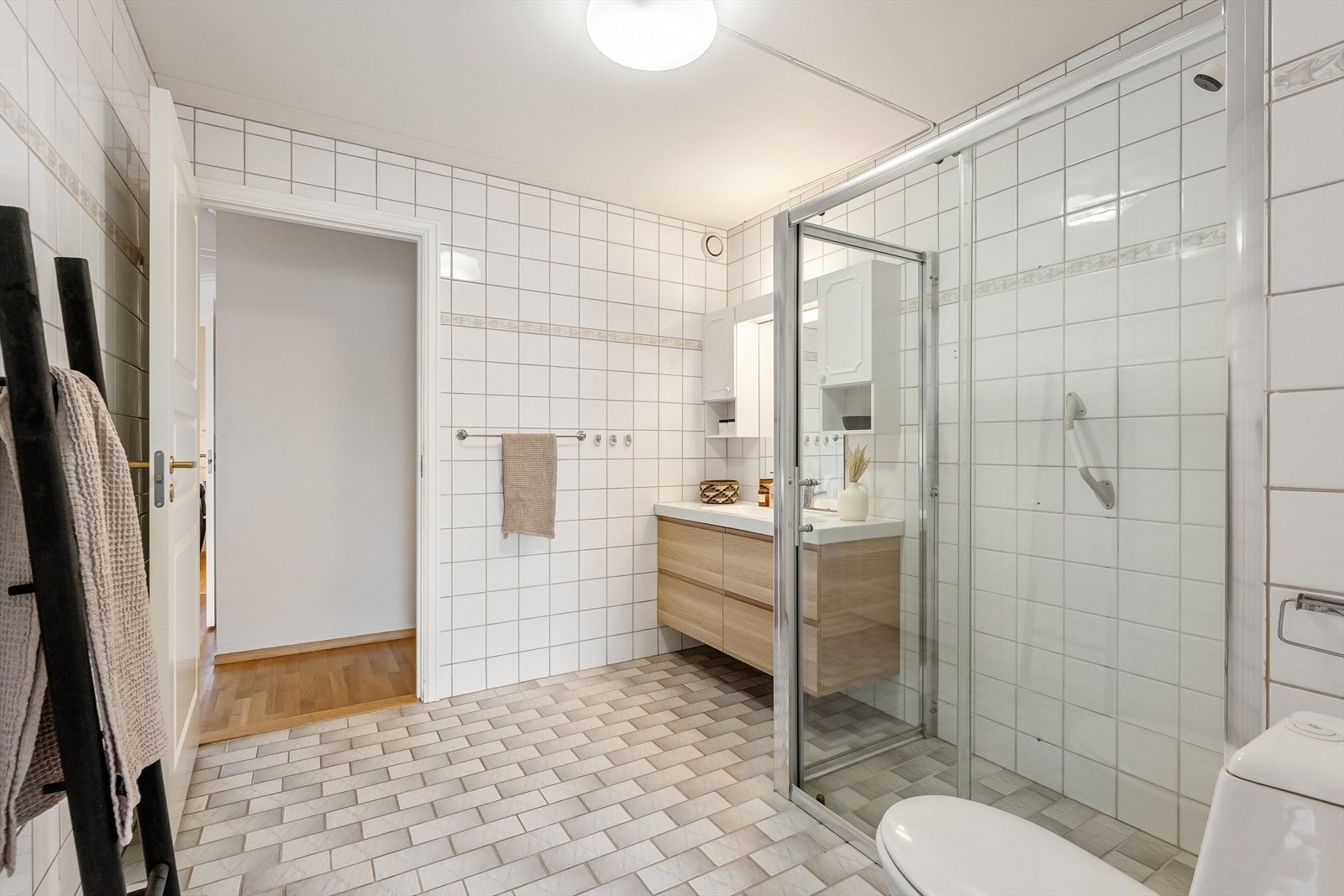 Badet er utstyrt med servantinnredning, overskap, gulvstående toalett og dusj. Galleribilde