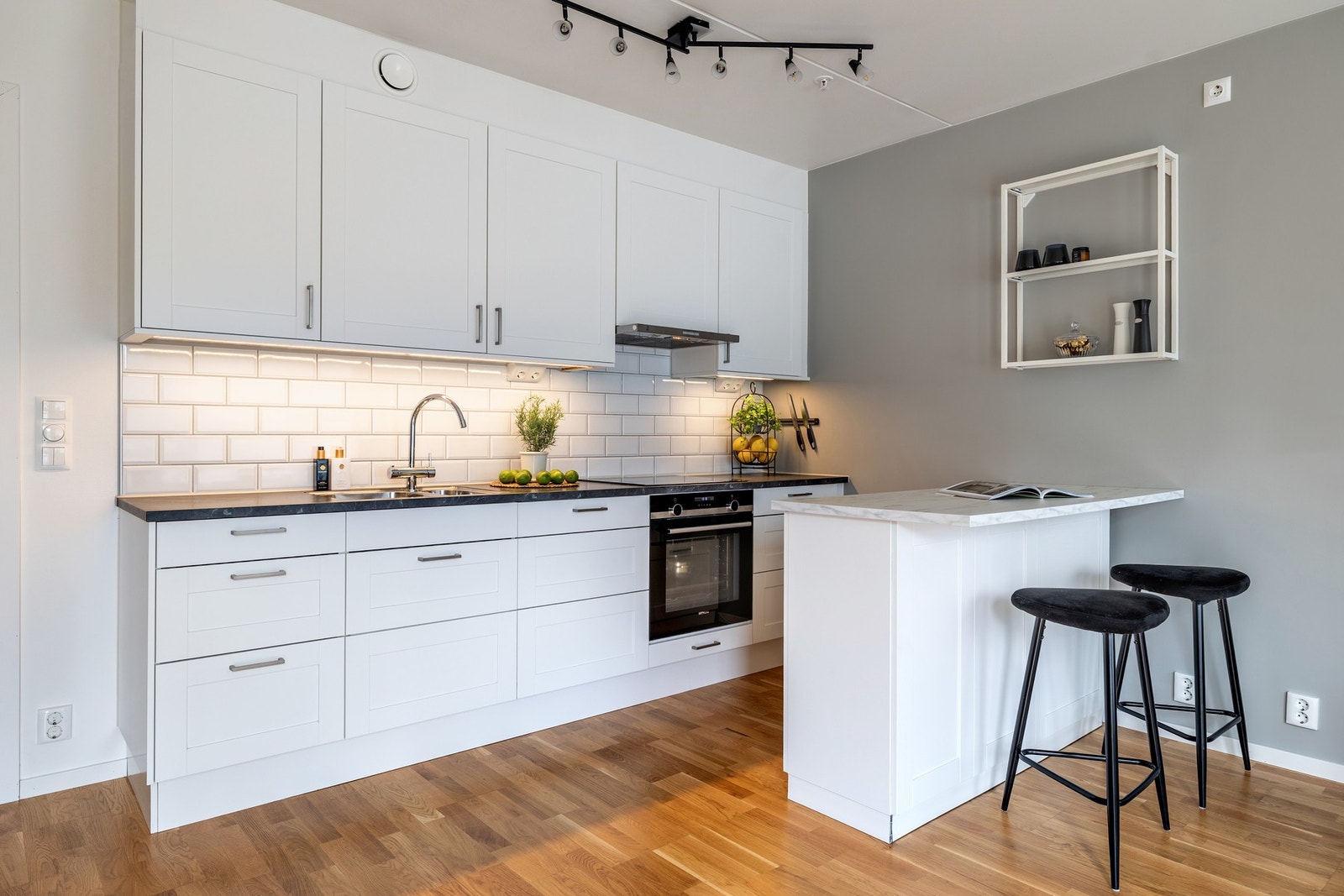 Det er praktisk belysning over benken, og det er flisfelt mellom overskap og kjøkkenbenk som gir et stilfullt preg. Galleribilde