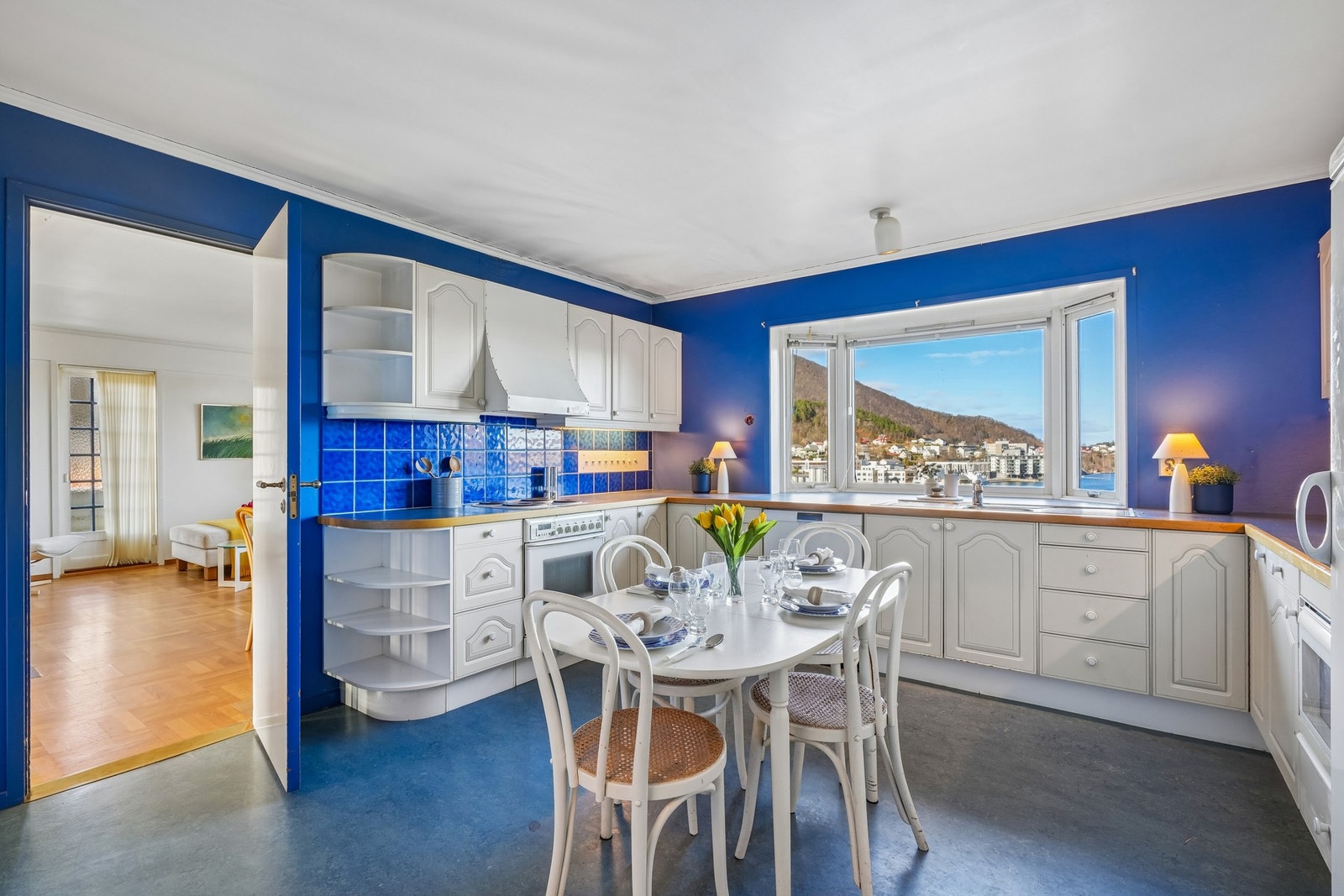 Kjøkkeninnredning med hvite profilerte fronter og fliser på vegg over laminat benkeplate. Galleribilde