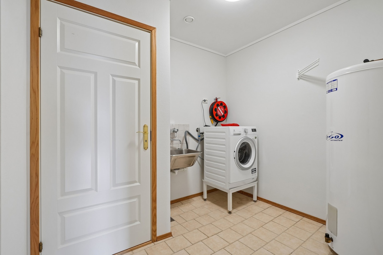 Vaskerom med fliset gulv med elektriske varmekabler og tapetserte vegger. Opplegg for vaskemaskin. Montert utslagsvask og varmtvannstank. Galleribilde