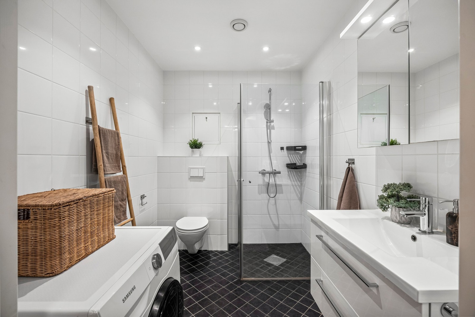 Romslig baderom bestående av servant, veggfestet klosett med innebygget sisterne og opplegg for vaskemaskin. Galleribilde