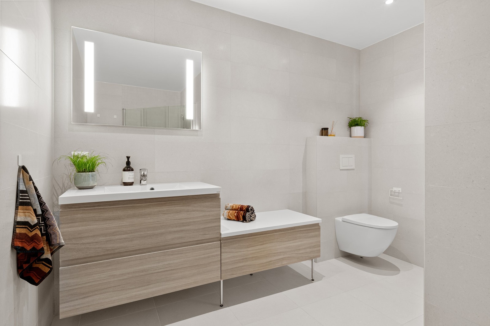 Helfliset baderom med vegghengt toalett, servant og dusjhjørne. Galleribilde