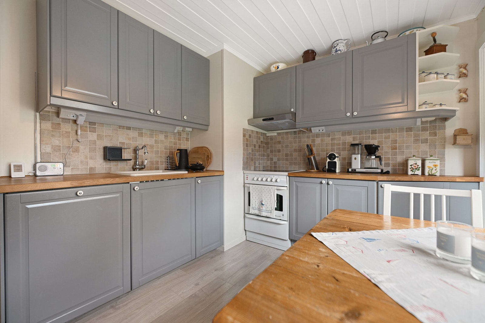 Innredningen har profilerte fronter, benkeplate i heltre og porselensvask, og det er fliser mellom over- og underskap som gir en slitesterk og lettstelt arbeidsone. Galleribilde