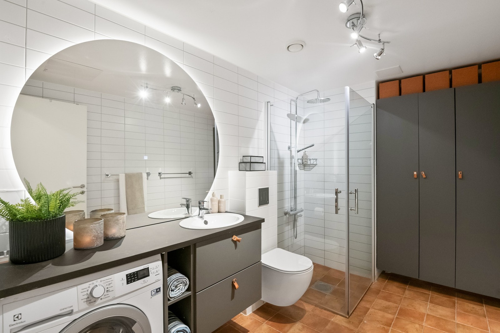 Badet er flislagt og fremstår funksjonelt med baderomsinnredning bestående av benkeskap og veggskap med glatte fronter. Galleribilde