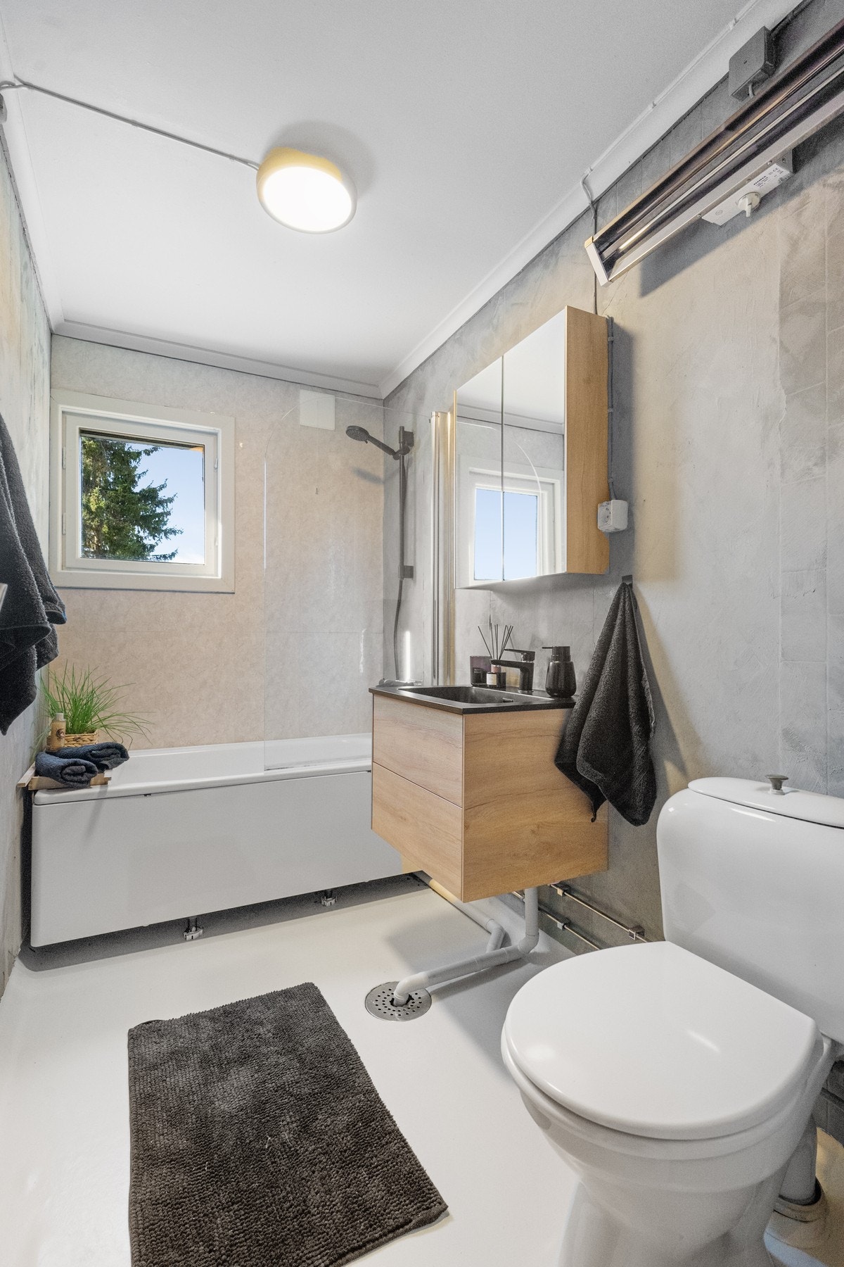 Badet er utstyrt med badekar, dusjløsning, servant med underskap og toalett. Galleribilde