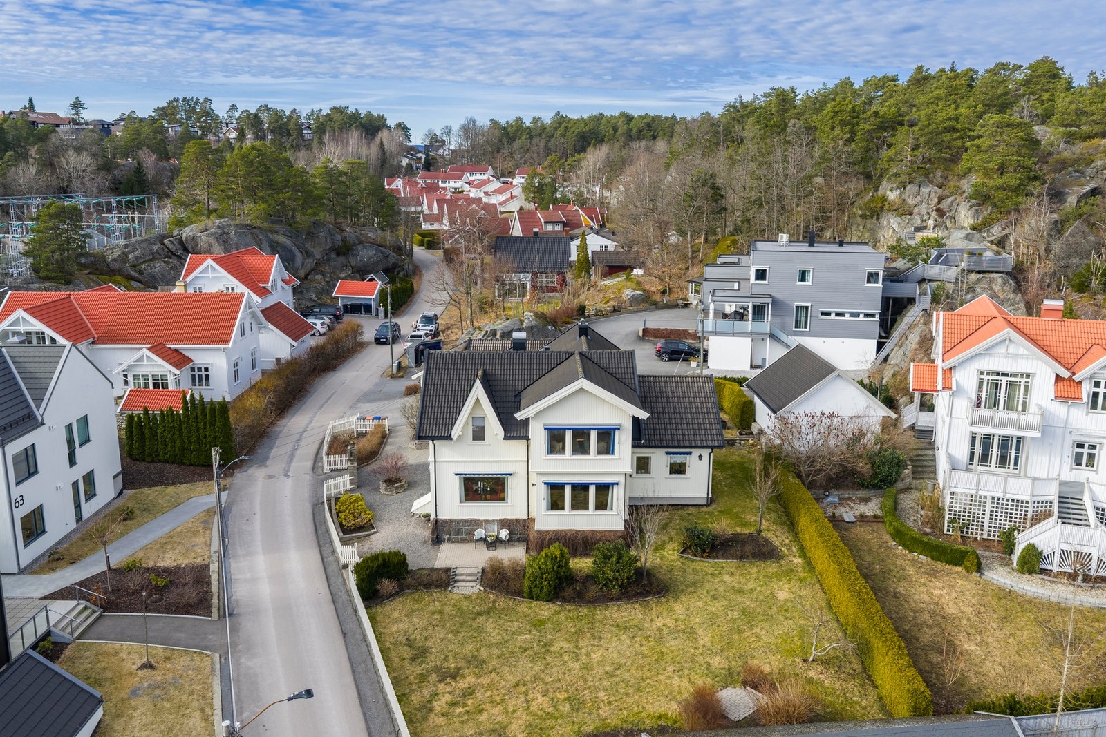 Eiendommen ligger i et rolig, barnevennlig område, med gjerde og hekk som avgrenser tomten og skaper en trygg uteplass Galleribilde