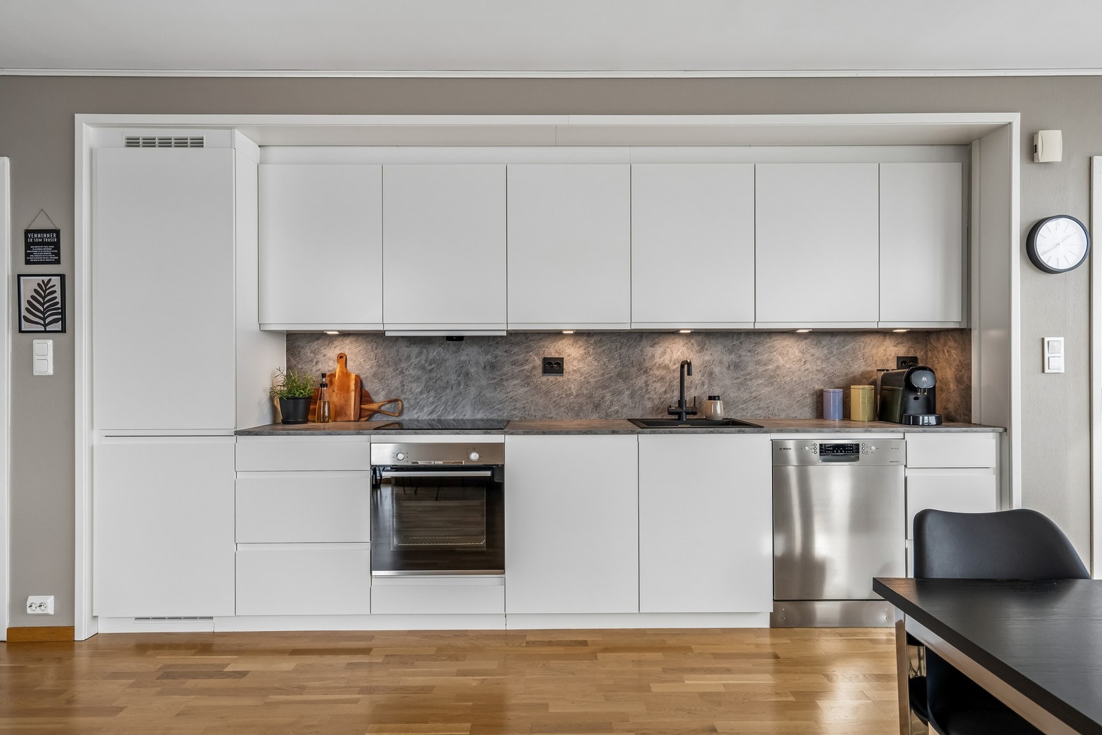 Kjøkken med stilig benkeplate og vegg mellom over og underskap. Galleribilde