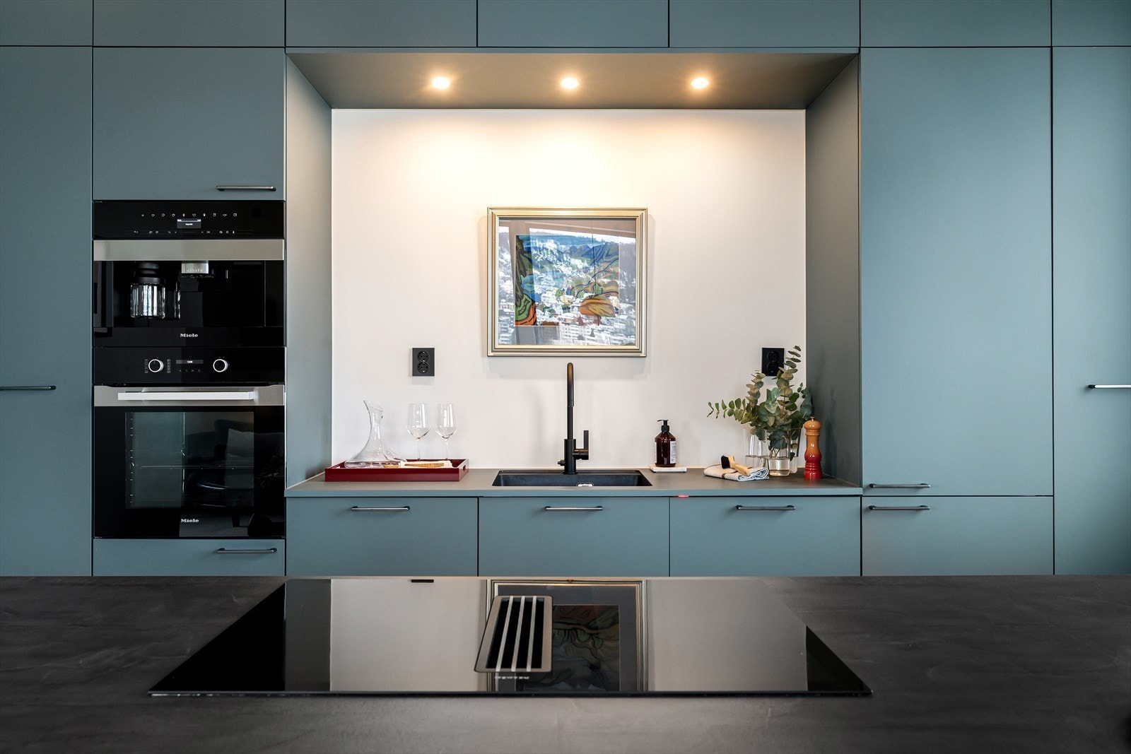 Fargevalget står i fin kontrast til benkeplaten og skaper en helhetlig og moderne atmosfære, samtidig som kjøkkenet oppleves både funksjonelt og innbydende. Galleribilde