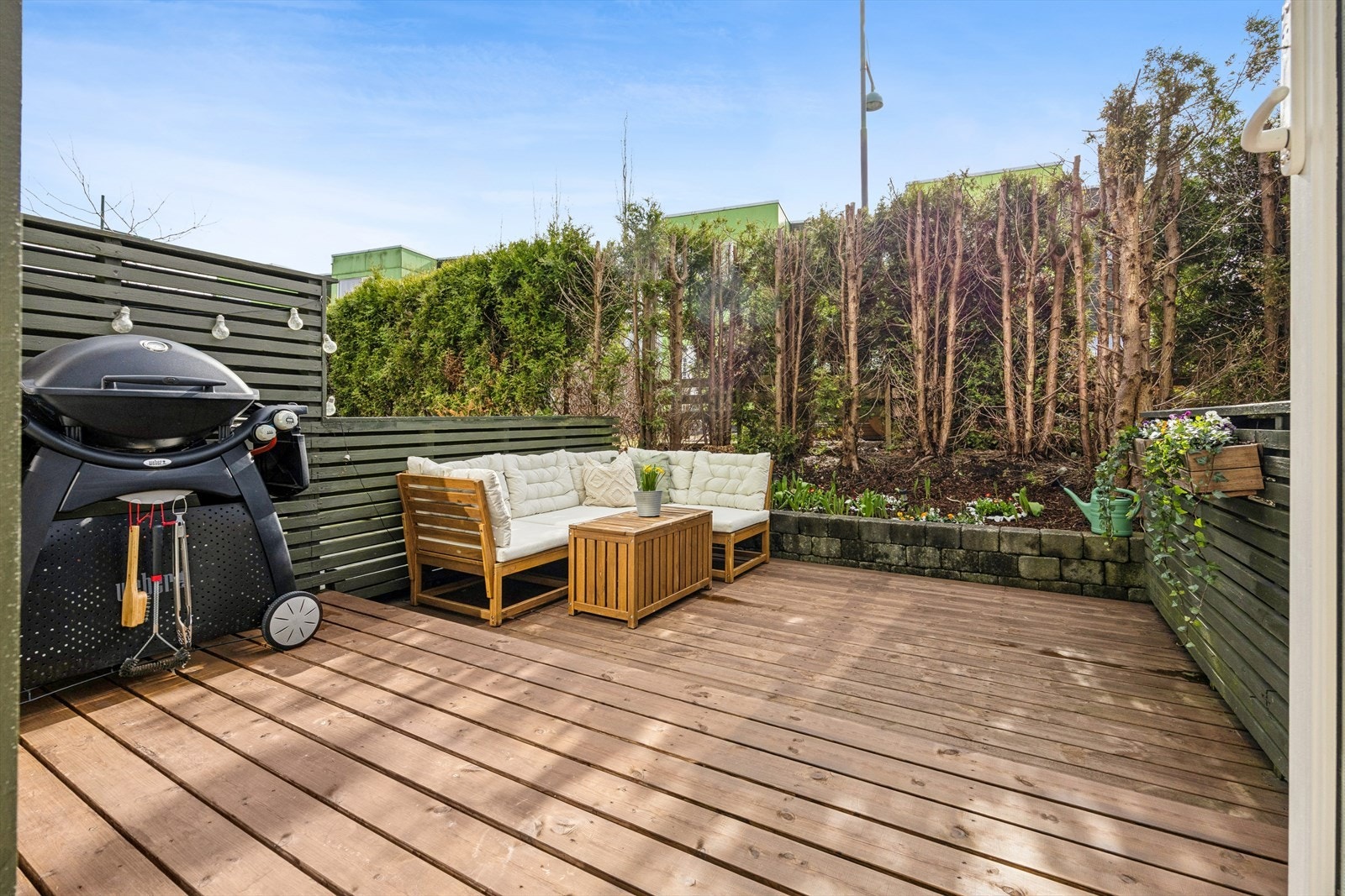 Terrassen på 14 m² er pent avgrenset med hekk og har nye terrassebord fra 2024. Galleribilde