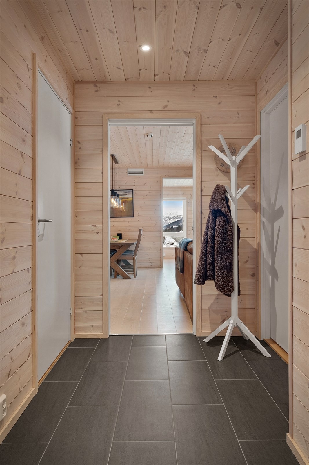 et er en romslig og lys entré med flislagt gulv med plass til å henge fra seg yttertøyet Galleribilde