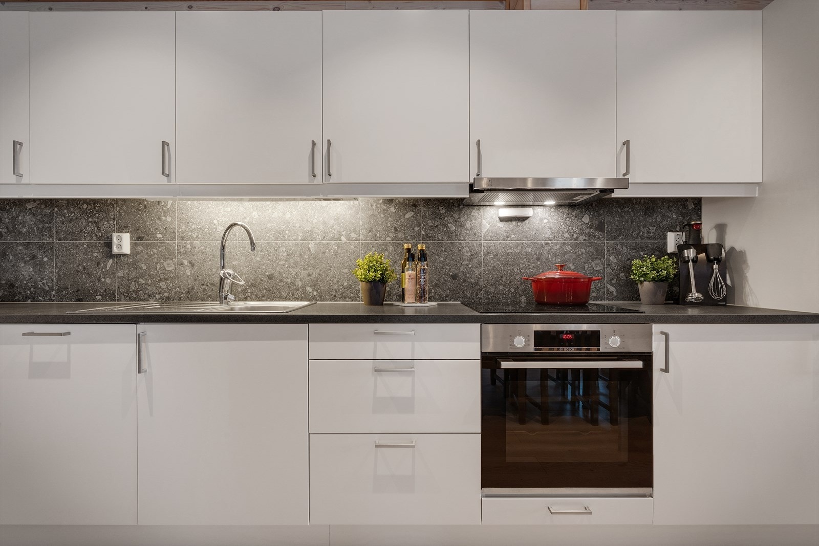 Kjøkkenet har hvite glatte fronter og laminert benkeplate med kjøkkenbeslag Galleribilde