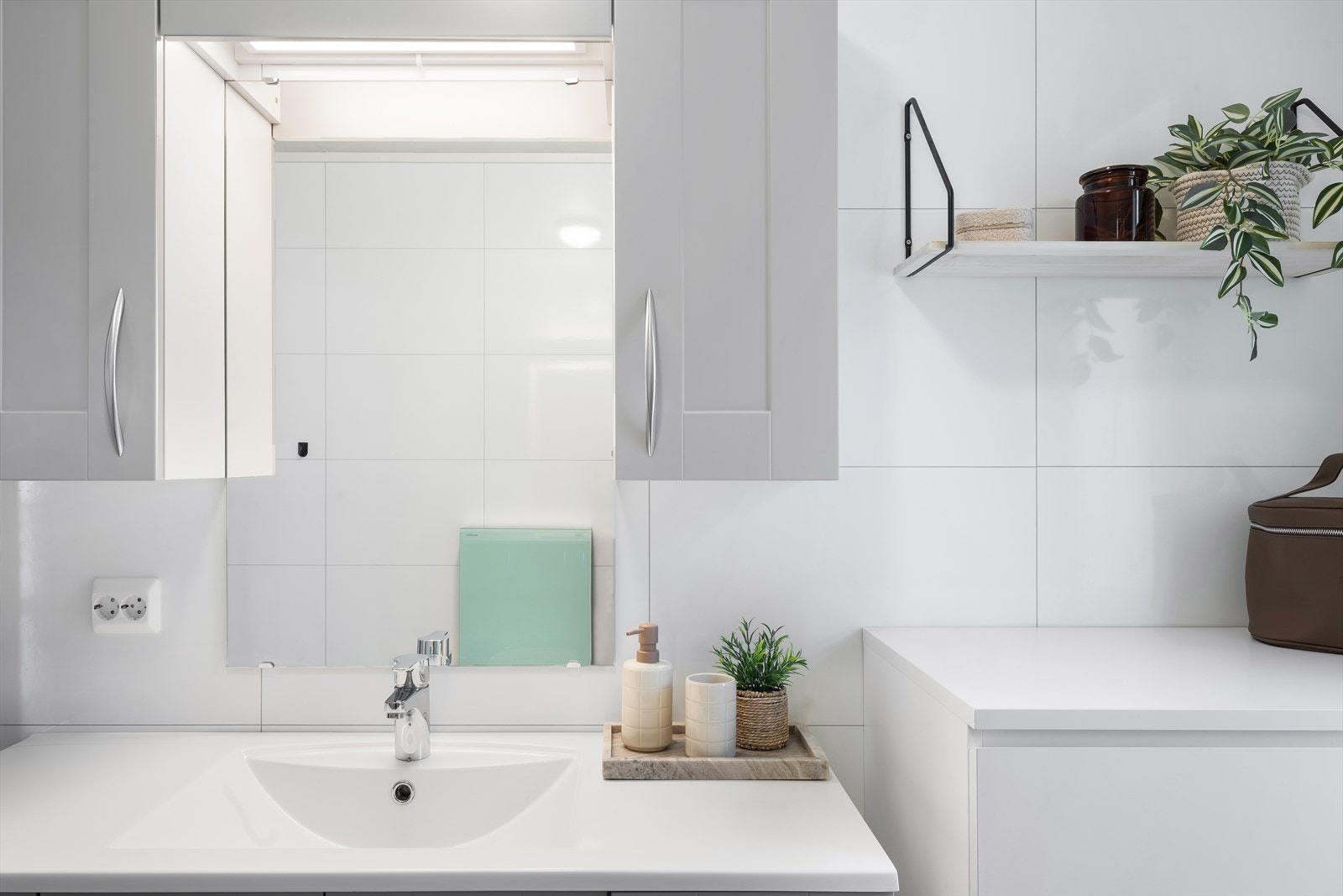 Lysegrå profilert innredning med heldekkende servant, underskap, overskap, speil og belysning. Vindu på badet som gir godt naturlig lys. Galleribilde