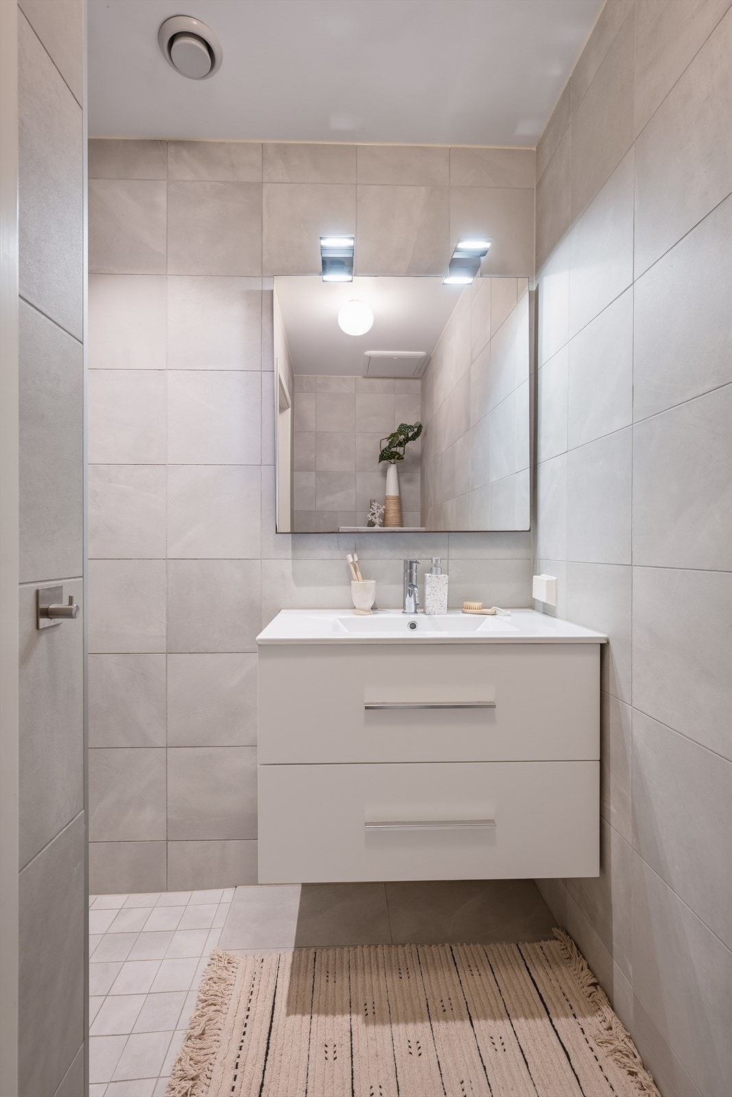 Flislagte vegger og gulv gir badet et delikat og lettstelt uttrykk. Det er varmekabler i gulvet. Galleribilde