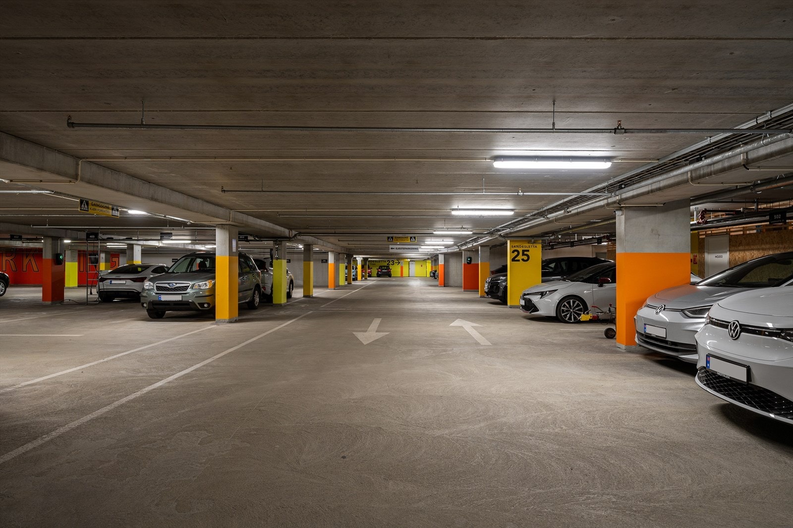 Parkering i lukket anlegg med infrastruktur for elbillader samt flere gjeste parkeringsplasser. Galleribilde