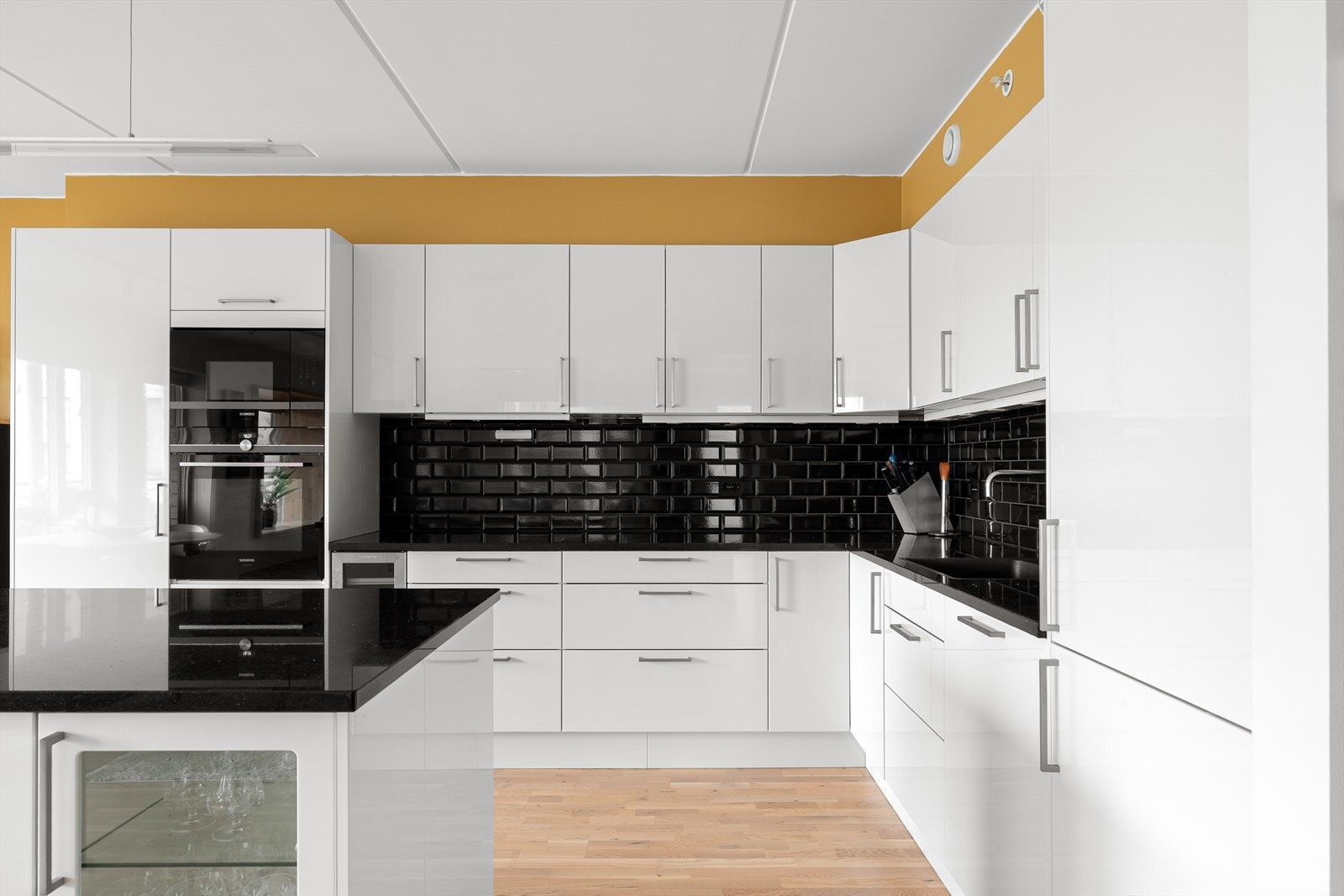 Lekkert Norema kjøkken med hvite fronter og mørk benkeplate i stein som gir en fin helhet i utrykket. Galleribilde